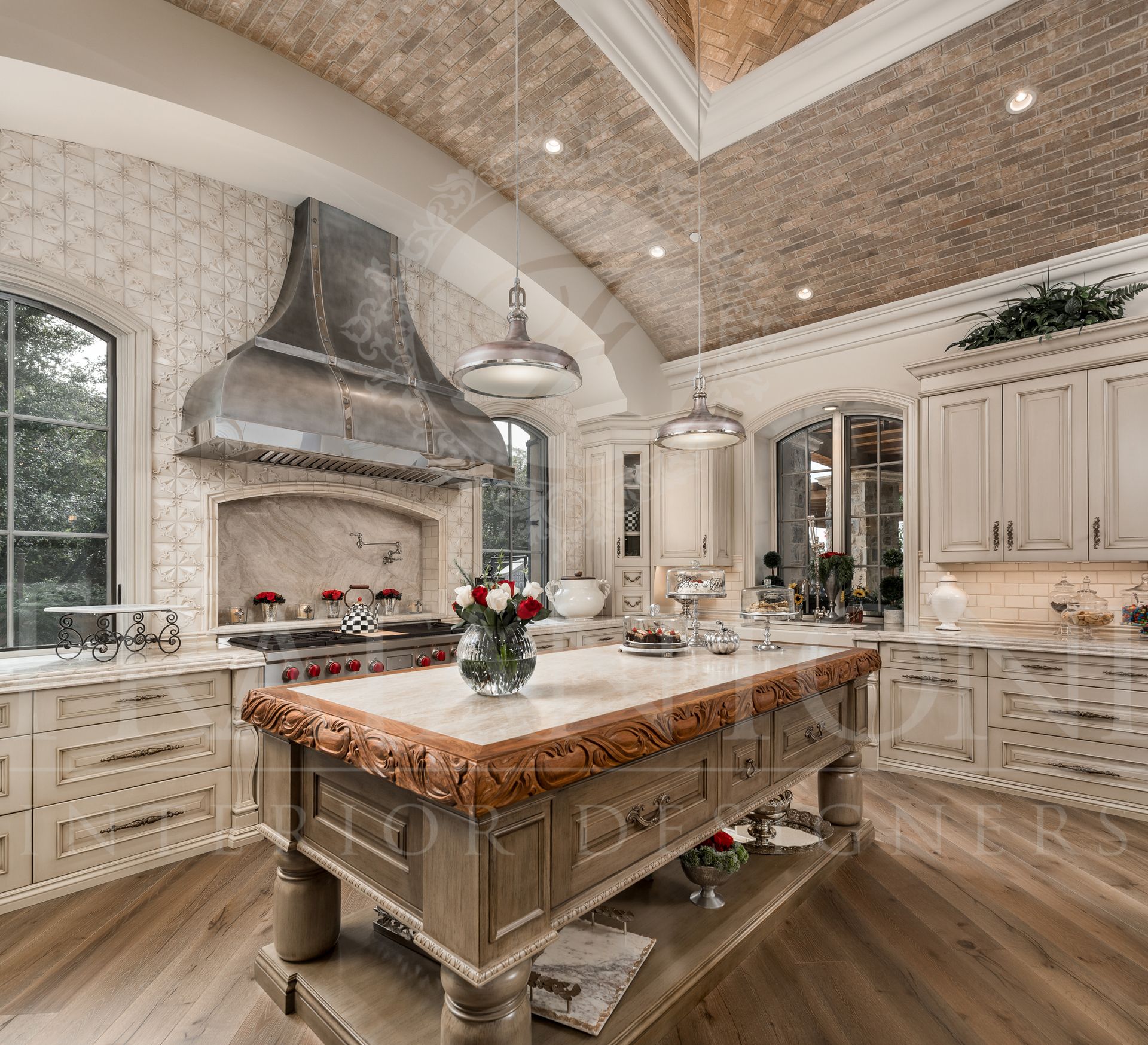 Luxurious custom kitchen with arched ceiling, neutral cabinets, large island, and stainless steel range hood.