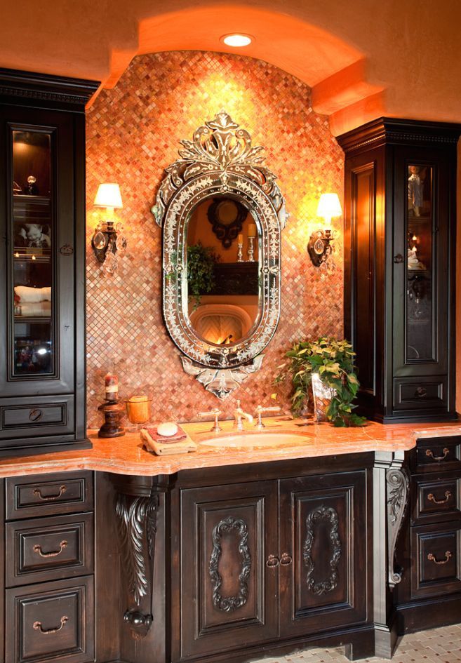 Bathroom vanity with ornate dark wood cabinets, a large mirror, and warm lighting.