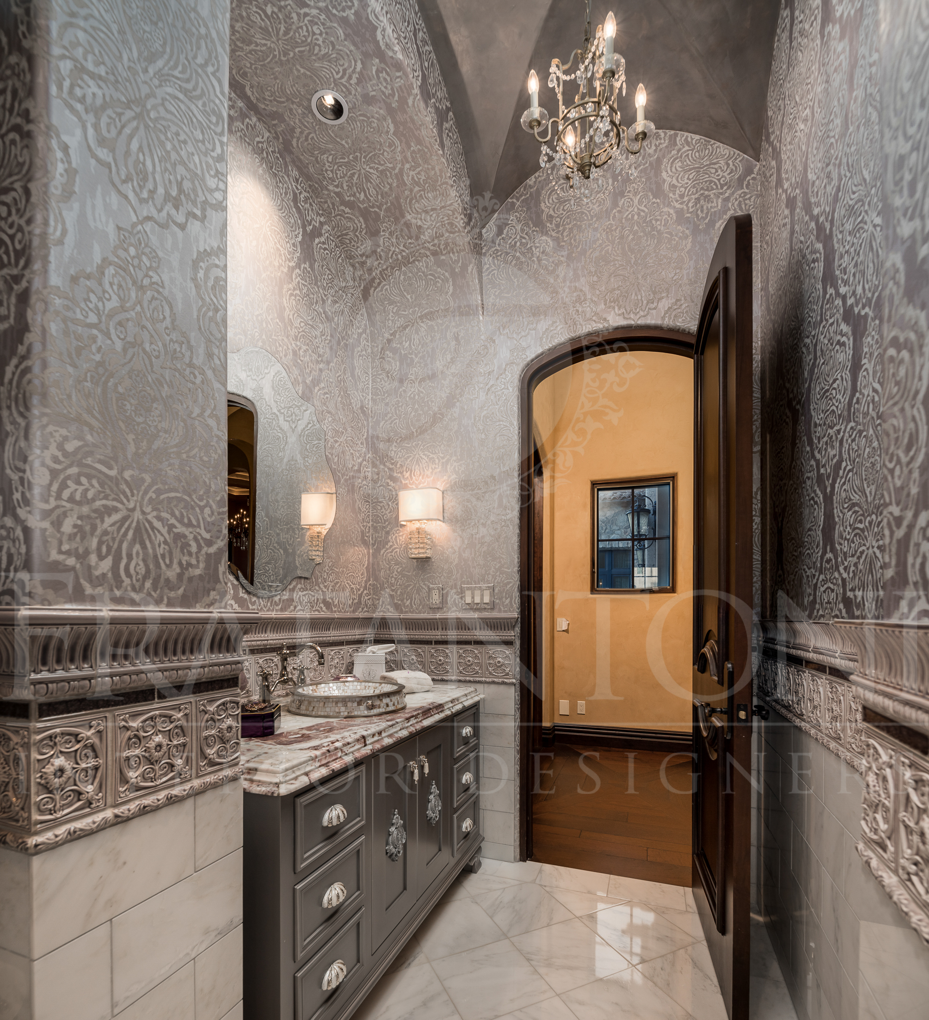 Elegant powder room with gray damask wallpaper, a marble vanity, and an open doorway.