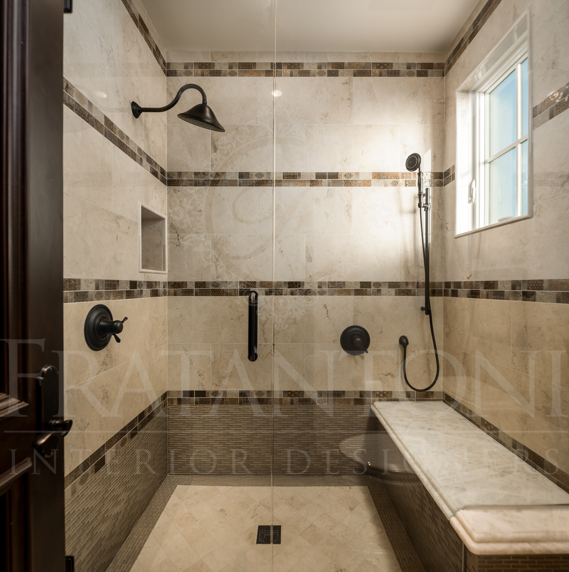 Shower with beige tile, dark fixtures, glass door, and a built-in bench.