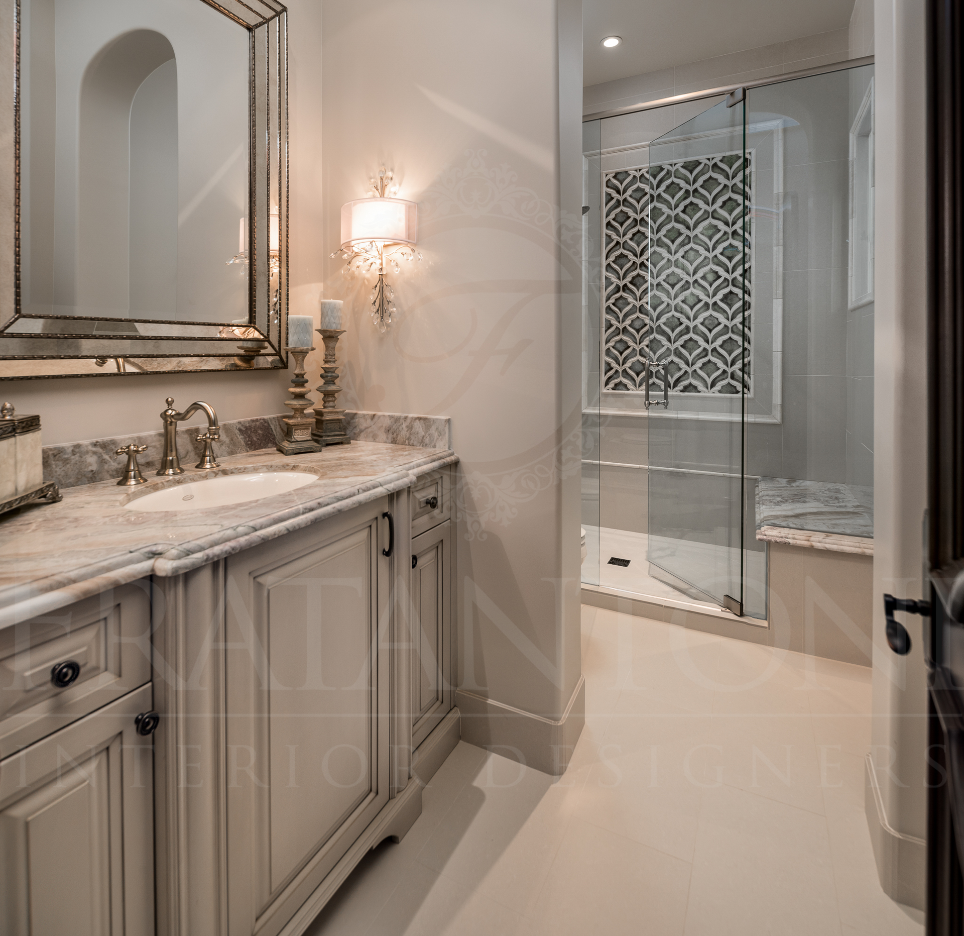 Elegant bathroom: vanity with mirror, sconces, marble countertop. Glass shower with patterned tiles.
