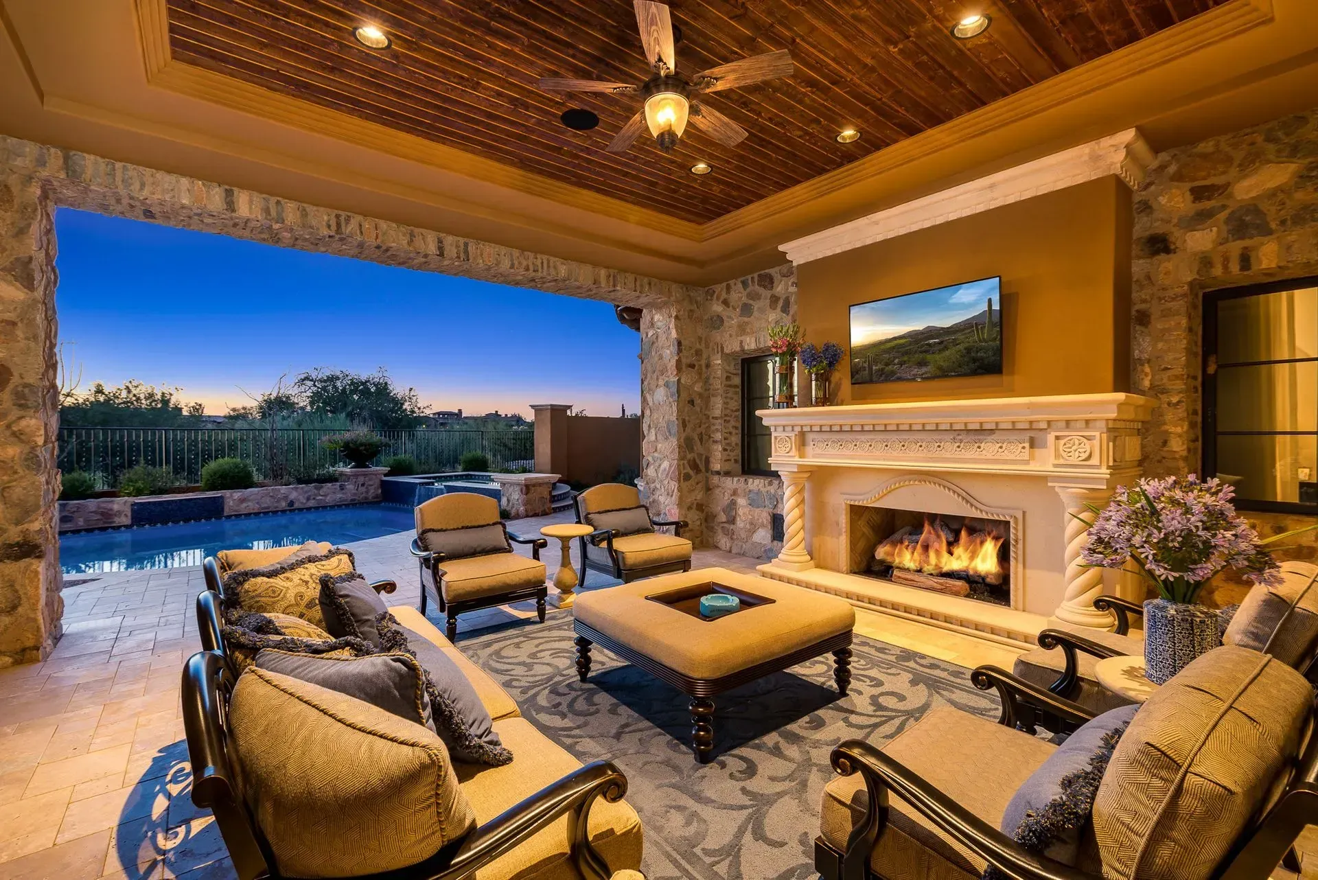 Outdoor patio with fireplace, seating, and pool view at dusk.