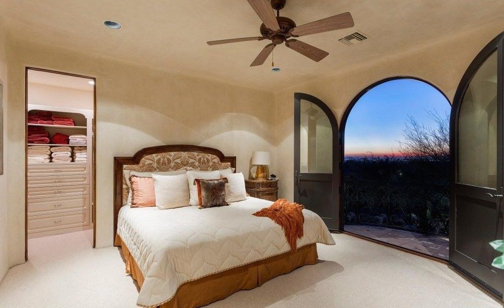 A bedroom with a large bed and a ceiling fan