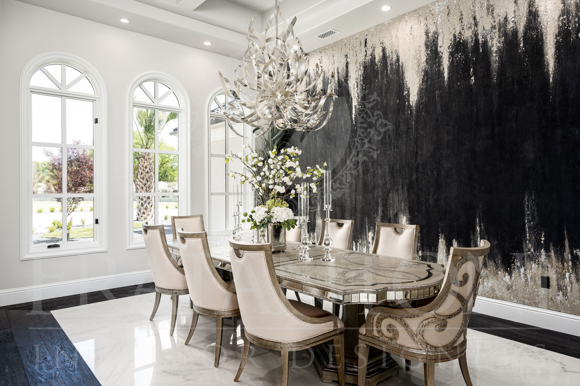 Elegant dining room with mirrored table, ornate chairs, dramatic chandelier, large windows, and a black and silver wall mural designed by Fratantoni Interior Designers in scottsdale, Arizona