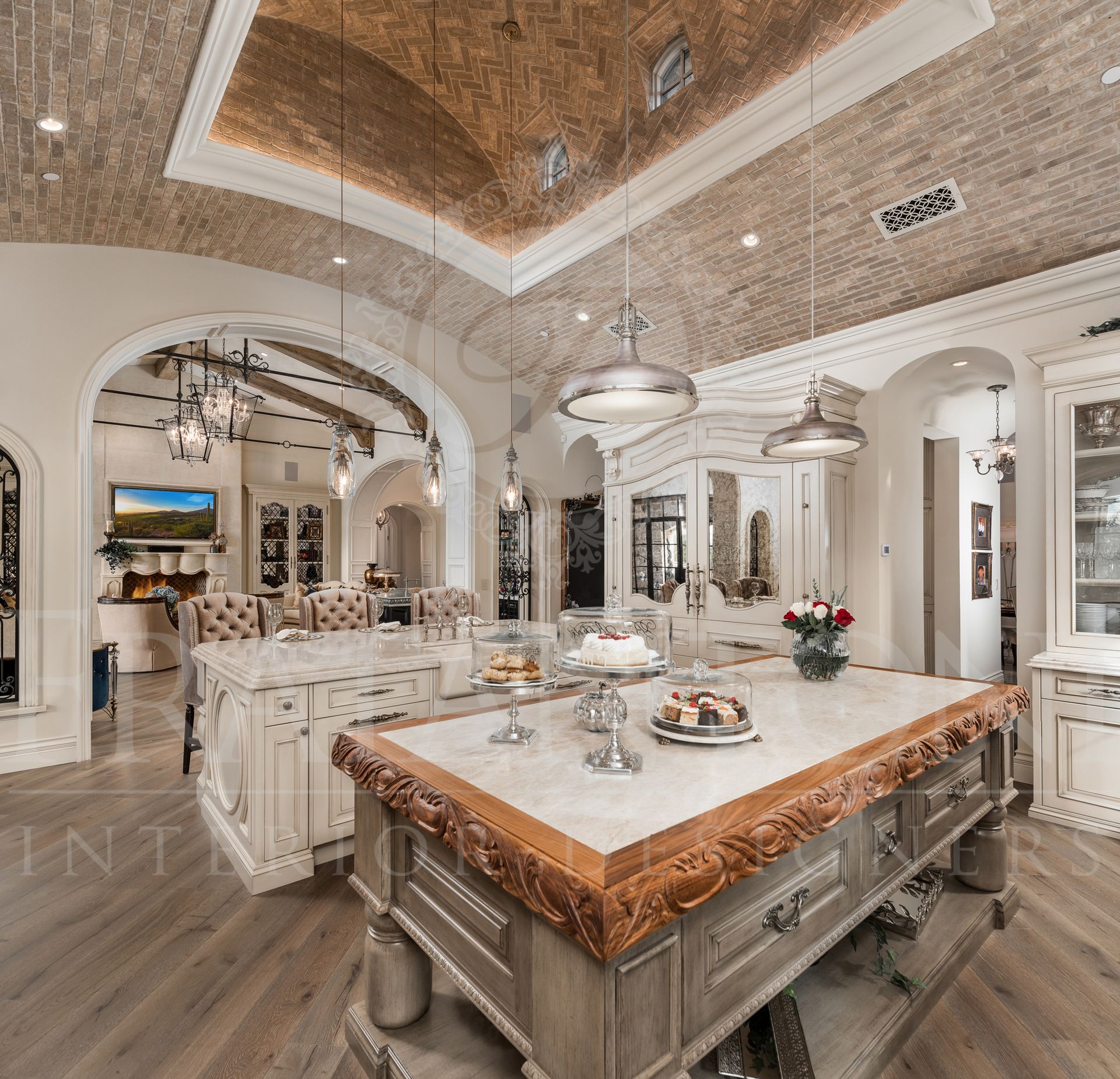 Luxury kitchen with large islands, brick vaulted ceiling, and view of living room with stone fireplace.