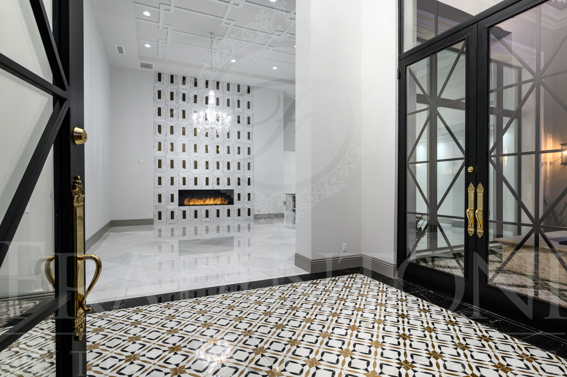 Luxury entry with patterned black-and-white floor, open black-framed doors, entering a custom great room with a custom fireplace in Scottsdale, Arizona