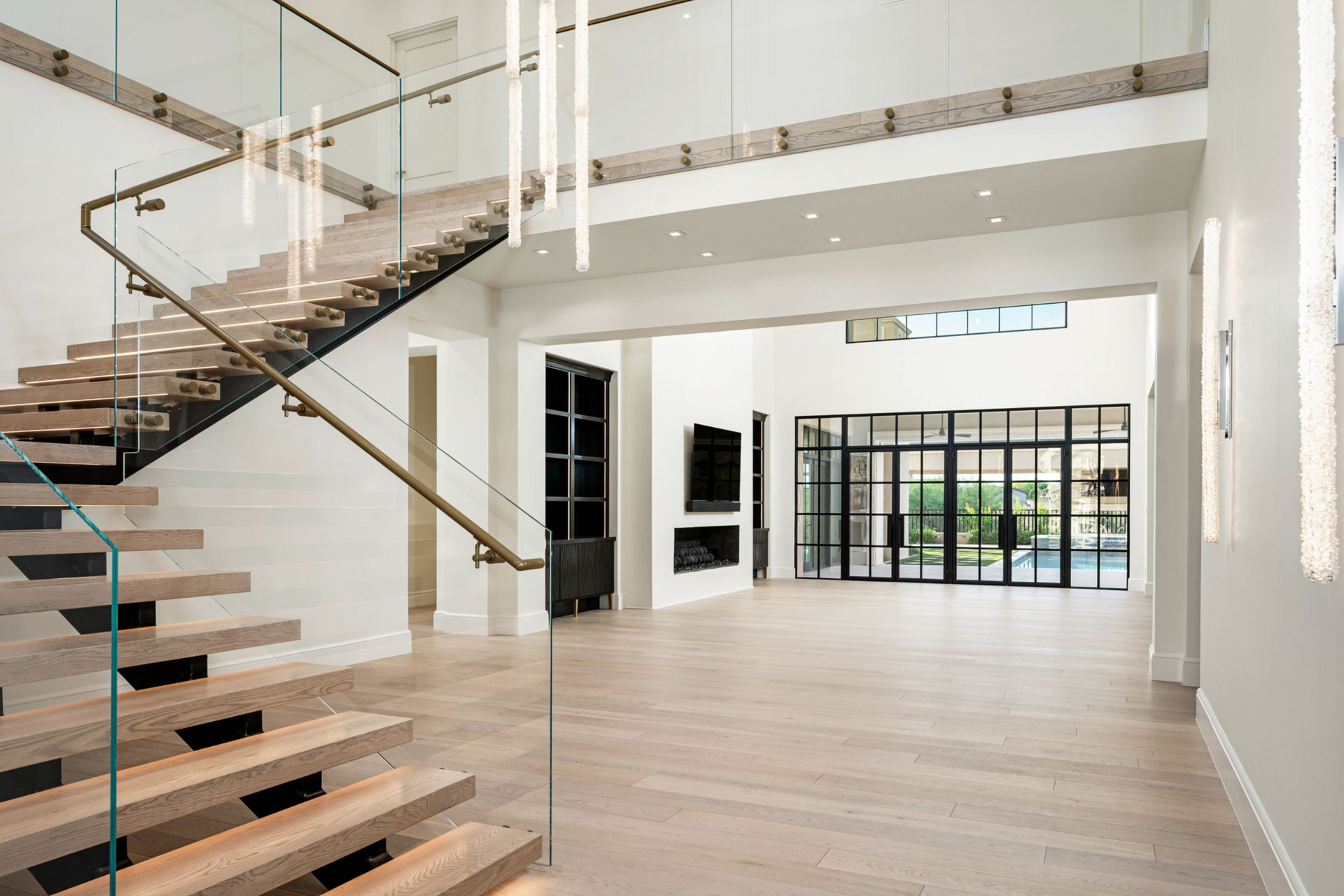 Spacious, modern kitchen with white marble floors, large chandeliers, and sliding glass doors.