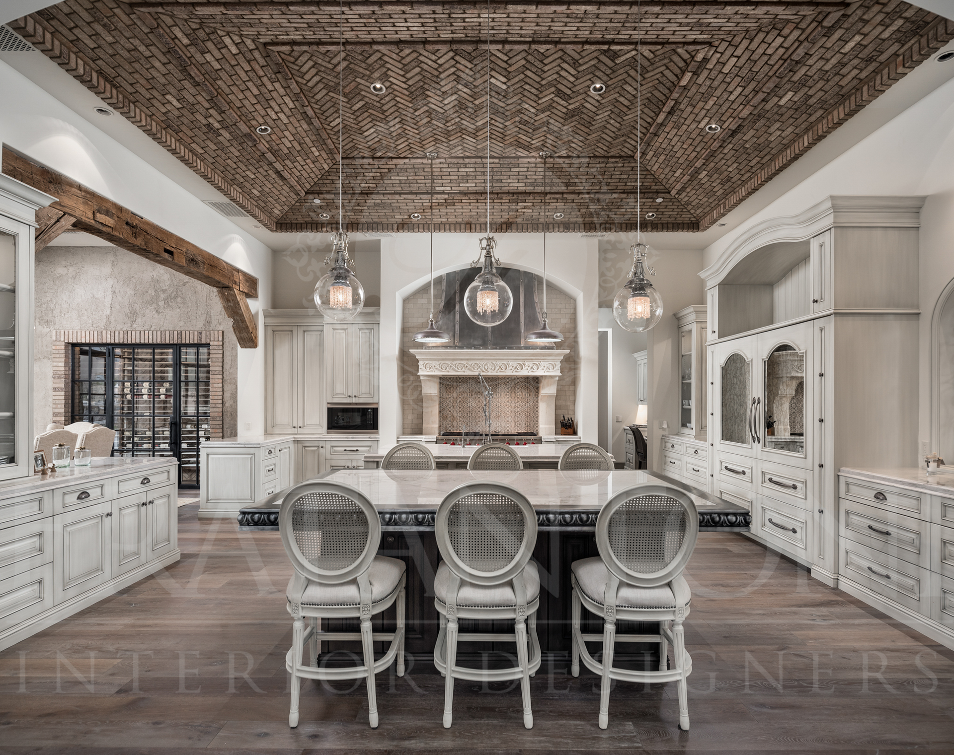 Elegant kitchen with brick ceiling, large island with three bar stools, white cabinets, and hangin pendant lights