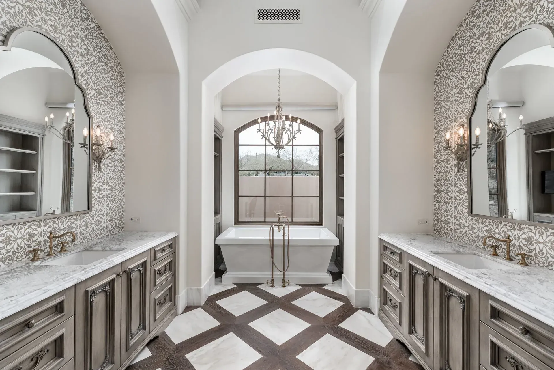 Luxurious bathroom with dual vanities, large arched mirrors, and a freestanding tub.