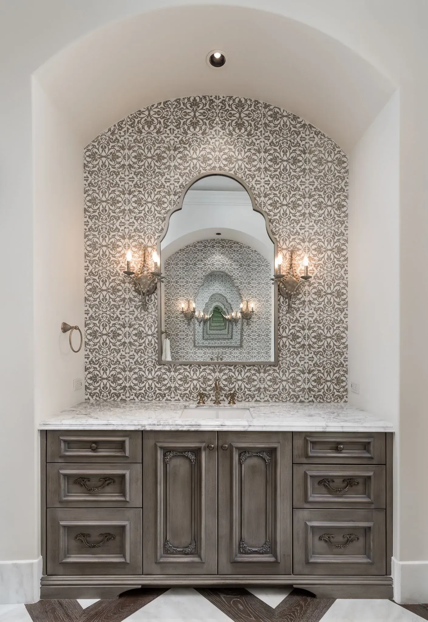 Bathroom vanity with gray cabinets, mosaic tile backsplash, and ornate mirror.