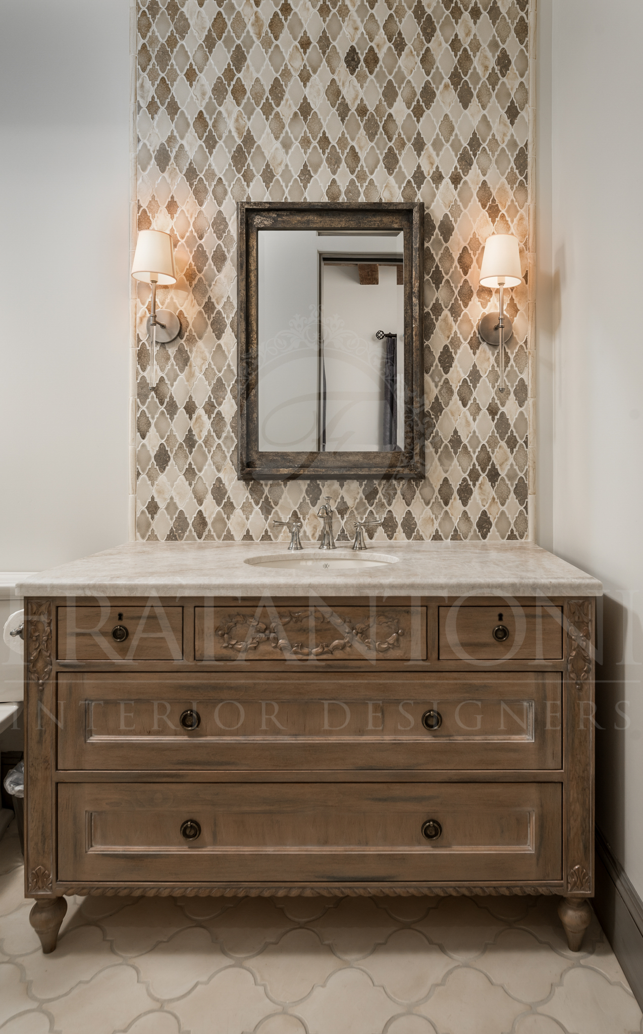 Bathroom vanity with patterned backsplash, mirror, and sconces. Wooden vanity with drawers, marble countertop.