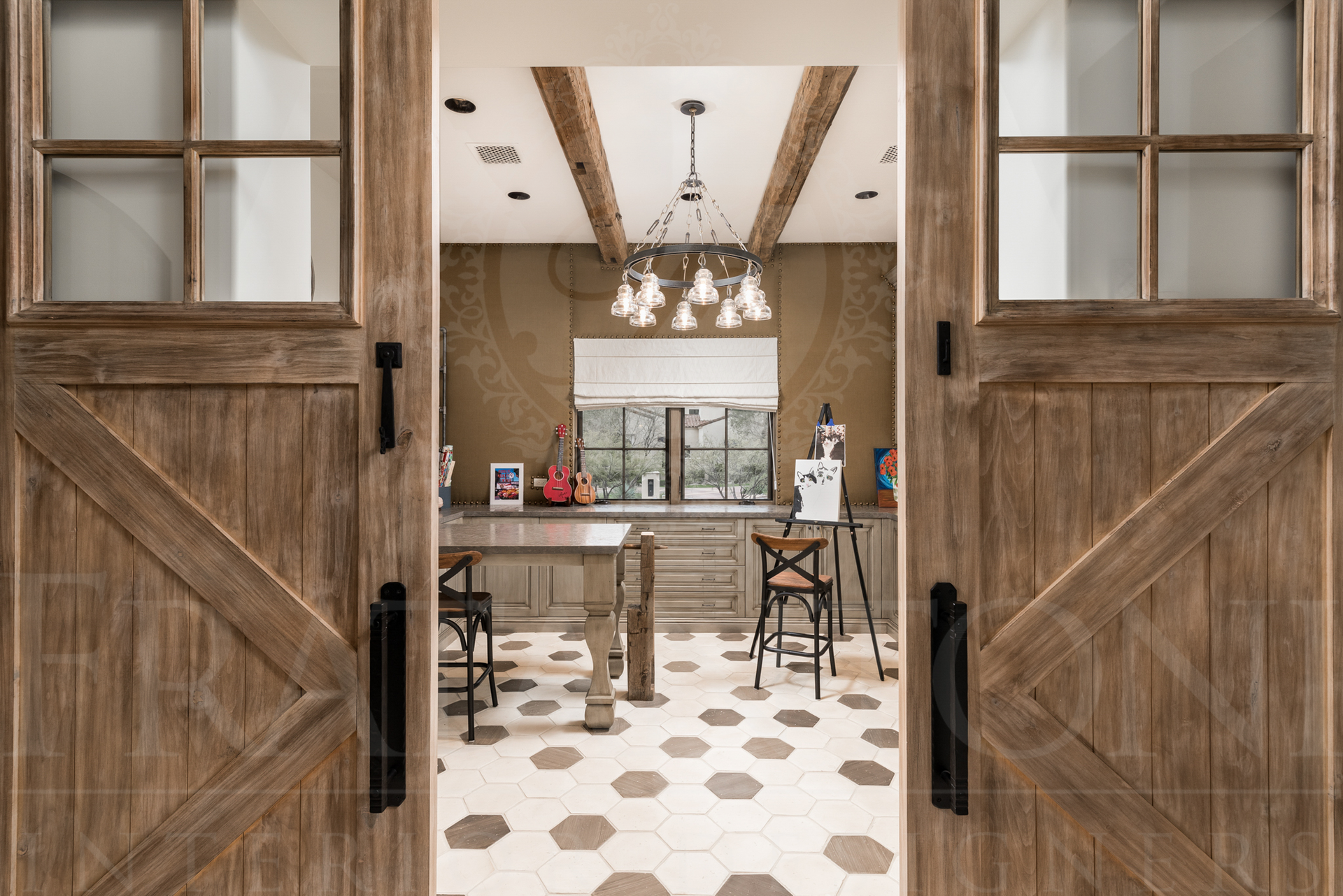 Open wooden barn doors lead into a home art studio with a table, easel, and chandelier.