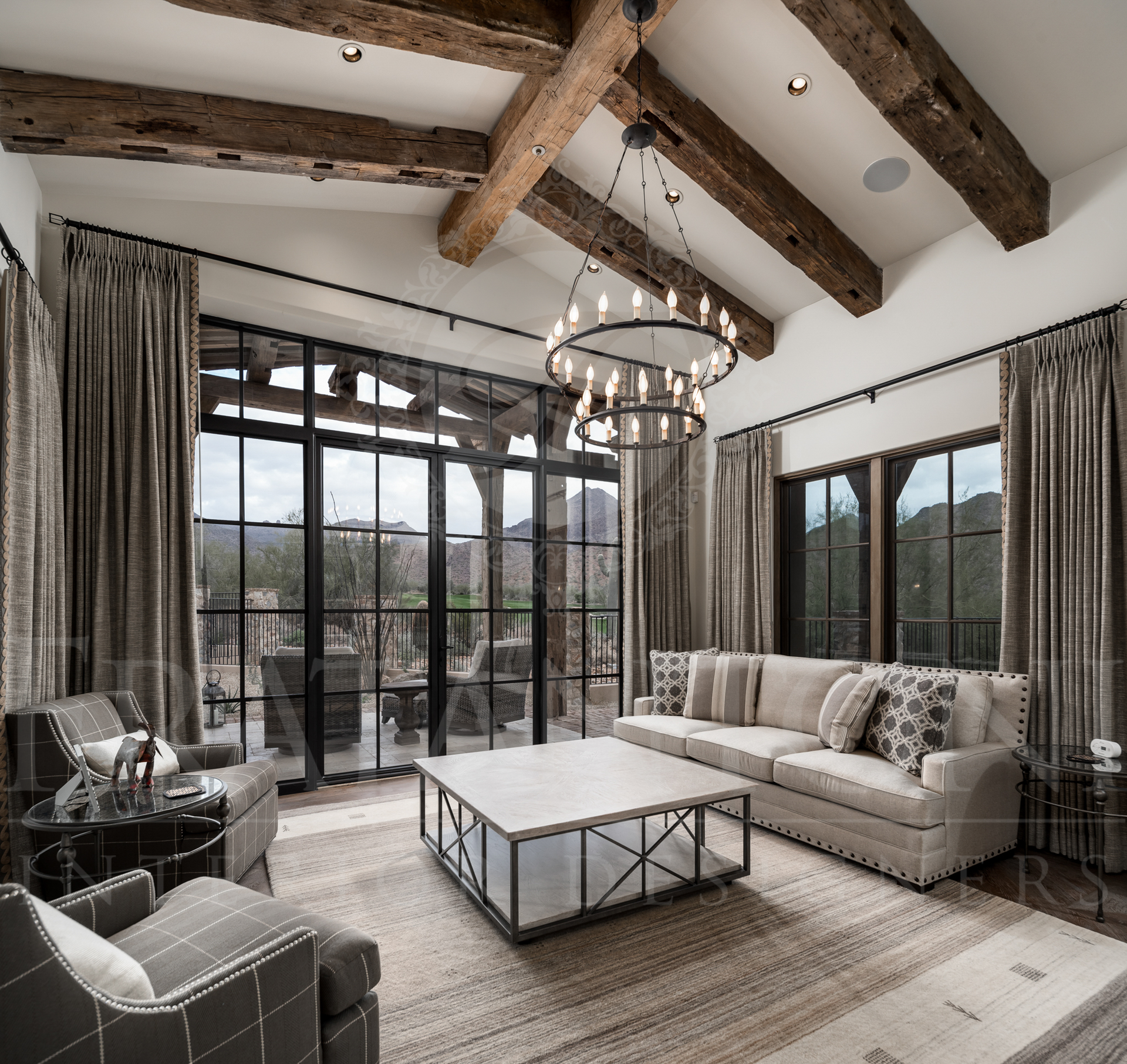 Living room with exposed wood beams, large windows, large glass doors with patio access, neutral furniture, and a desert outdoor view designed by Fratantoni Interior Designers in scottsdale arizona. 