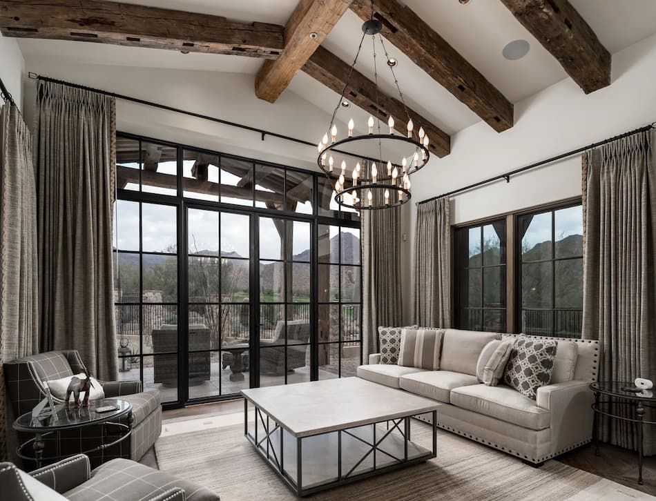 Living room with large windows, exposed beams, and a neutral color scheme.