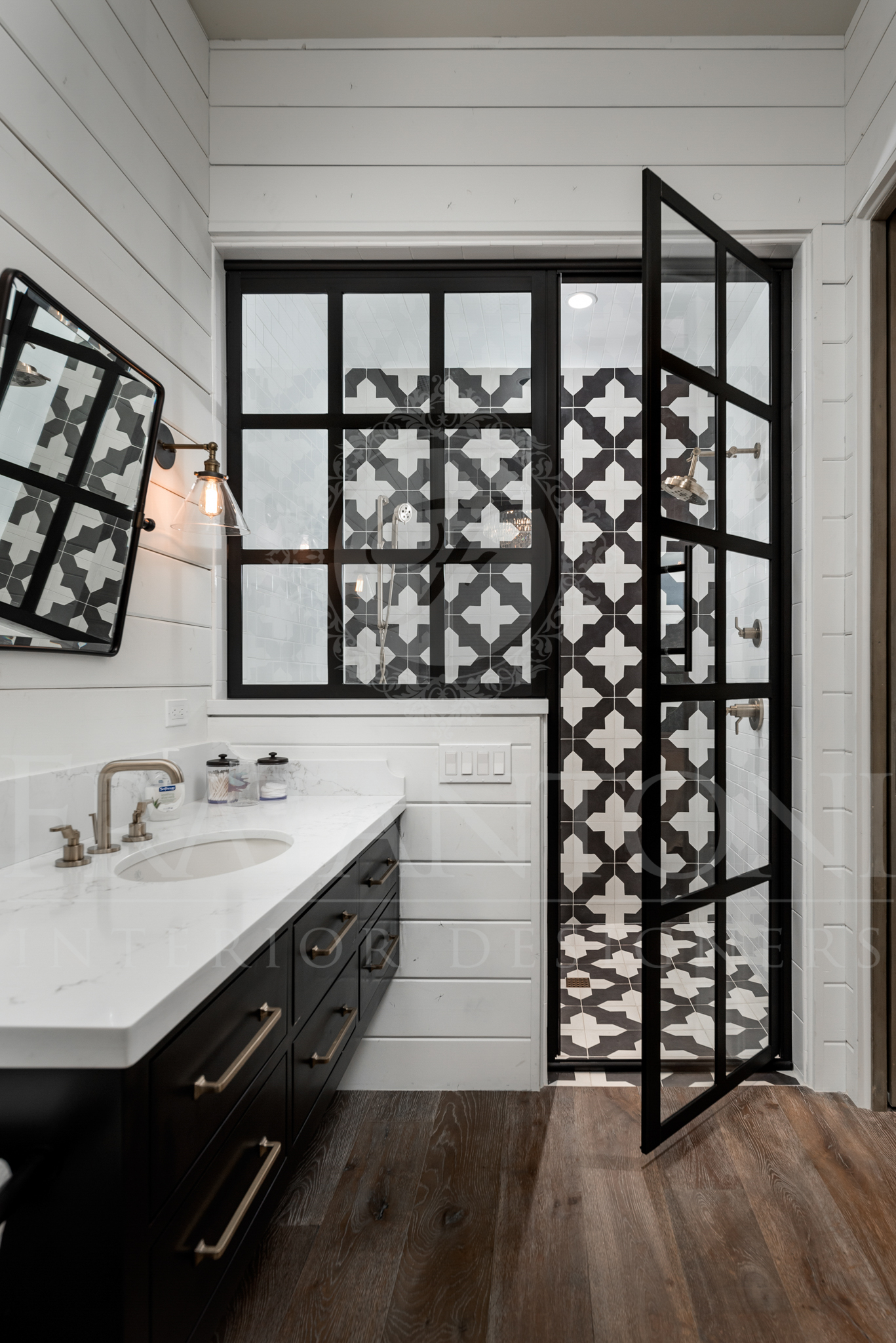 Bathroom with black-framed shower door, white shiplap walls, black vanity, and patterned shower tile.
