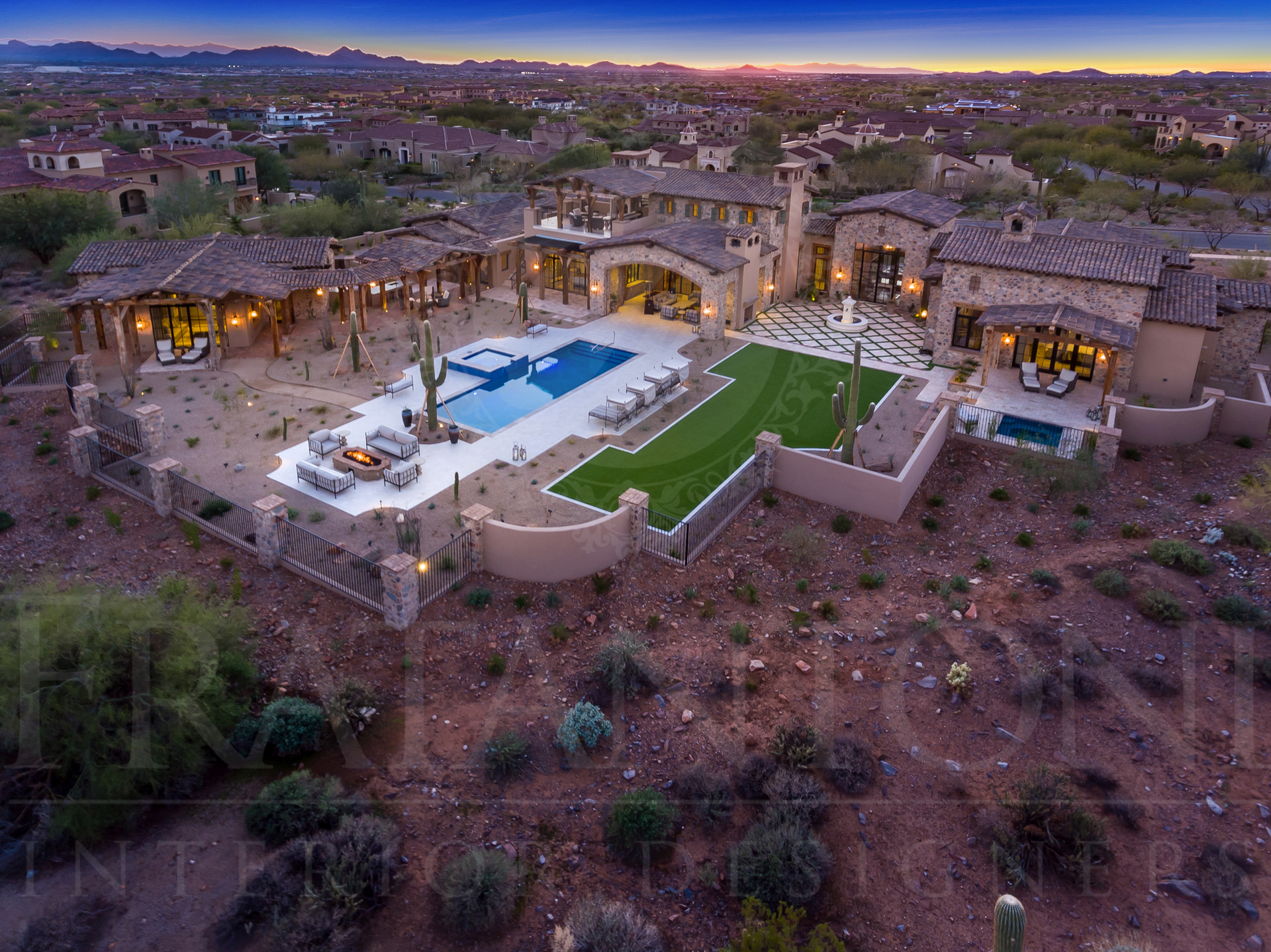 Aerial view of a luxury arizona home with a pool, patio, in a desert landscape at dusk.