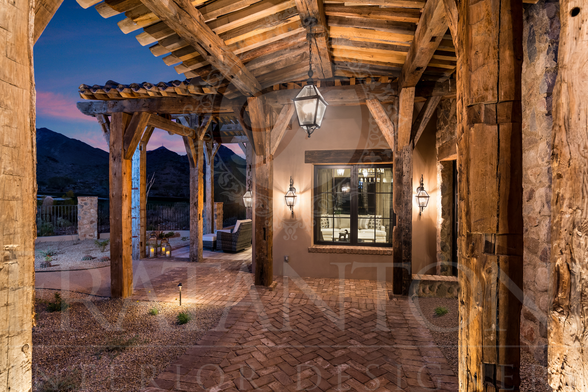 Covered porch with rustic wooden beams and brick flooring, overlooking desert mountains at dusk designed by Fratantoni Interior Designers in scottsdale arizona