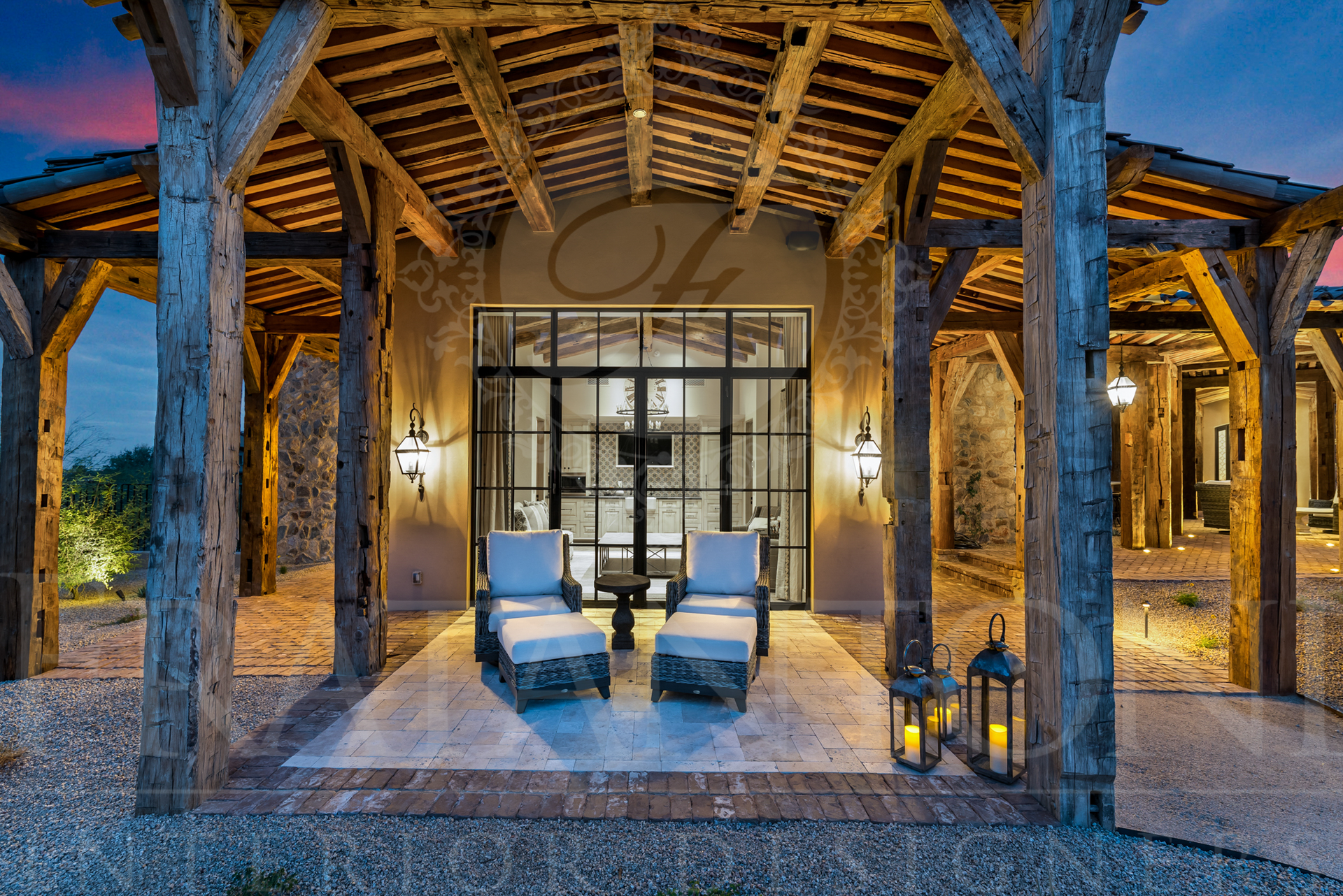 Casita patio with wooden columns, timber beams, lounge chairs, glass doors, and lanterns at dusk.