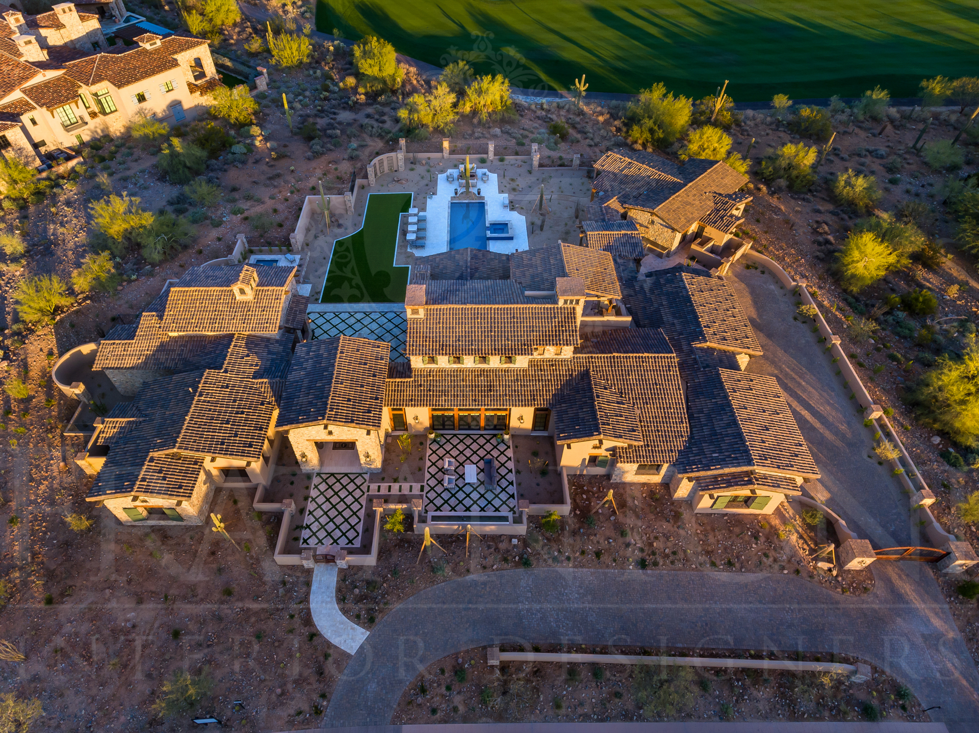 Aerial view of a large, multi-winged home with a resort-style pool, set in a dry, desert-like landscape in arizona. 