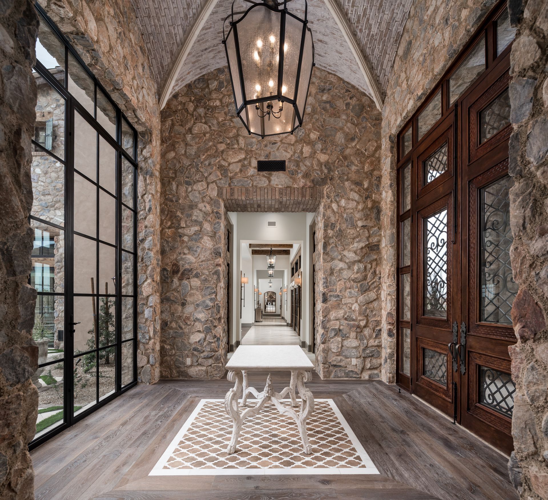 Elegant stone hallway with arched ceilings, wrought-iron lantern, wooden doors, custom mosaic inlay