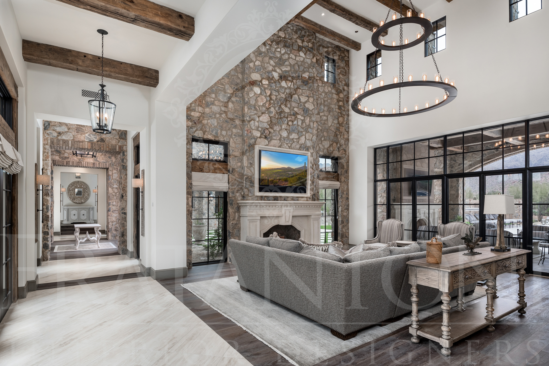 Spacious living room with stone wall, fireplace, and large windows.  Neutral colors and rustic beams designed by Fratantoni Interior Designers in scottsdale, Arizona. 