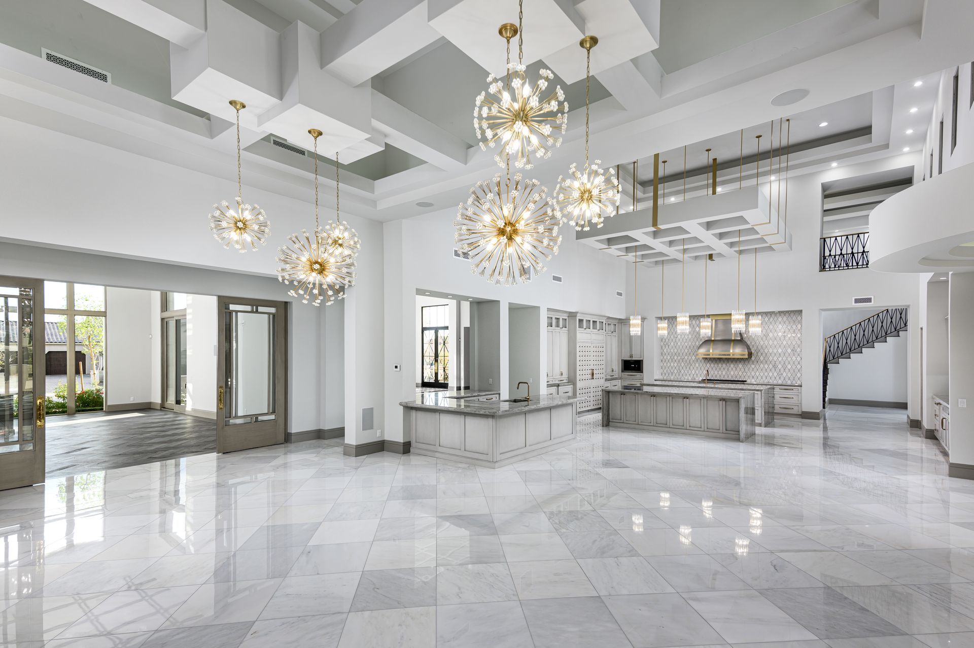 A large great room and kitchen with marble floors and modern chandeliers