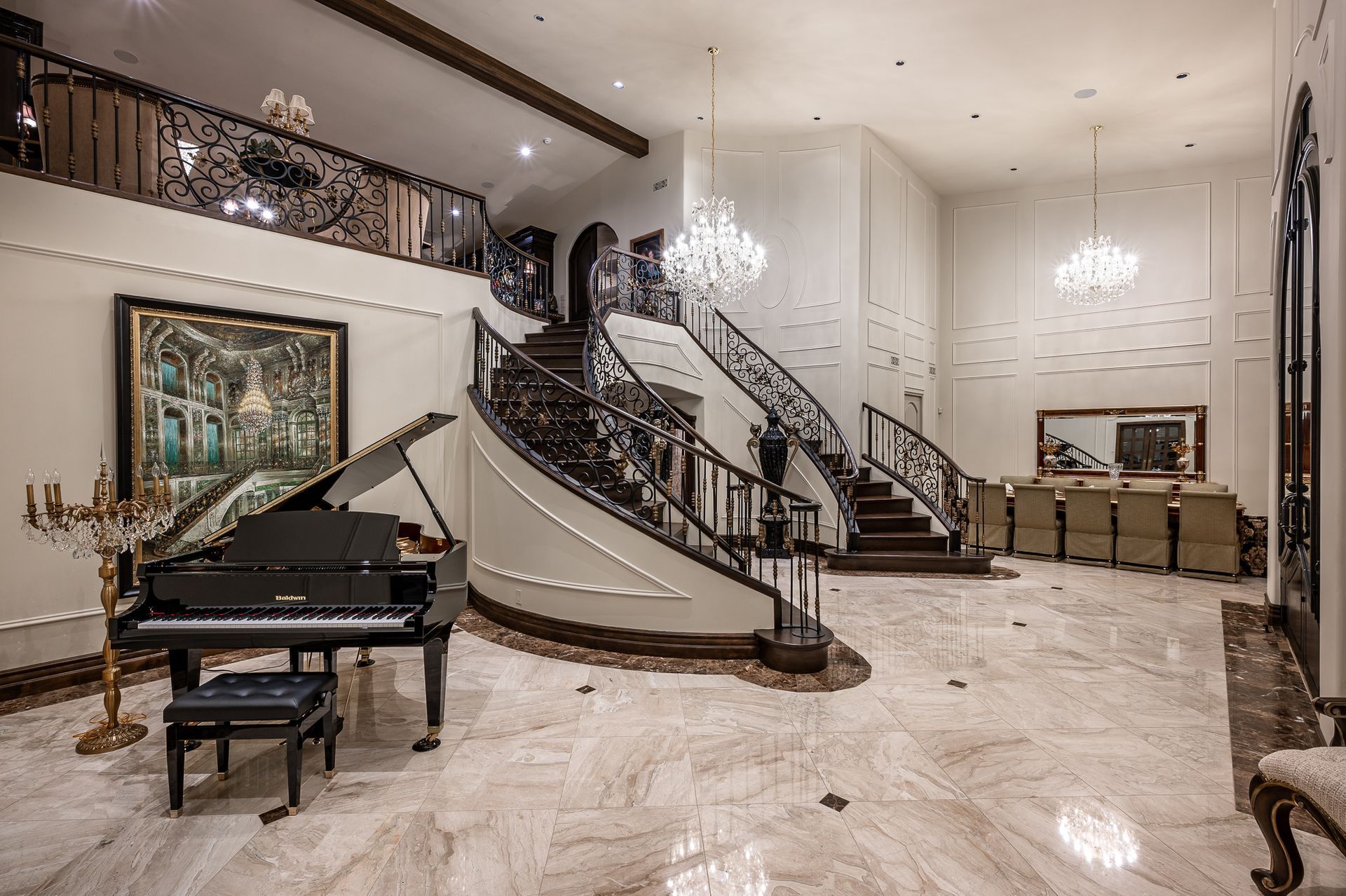 Grand foyer with curved staircase, chandeliers, piano, and marble floor in a luxury home