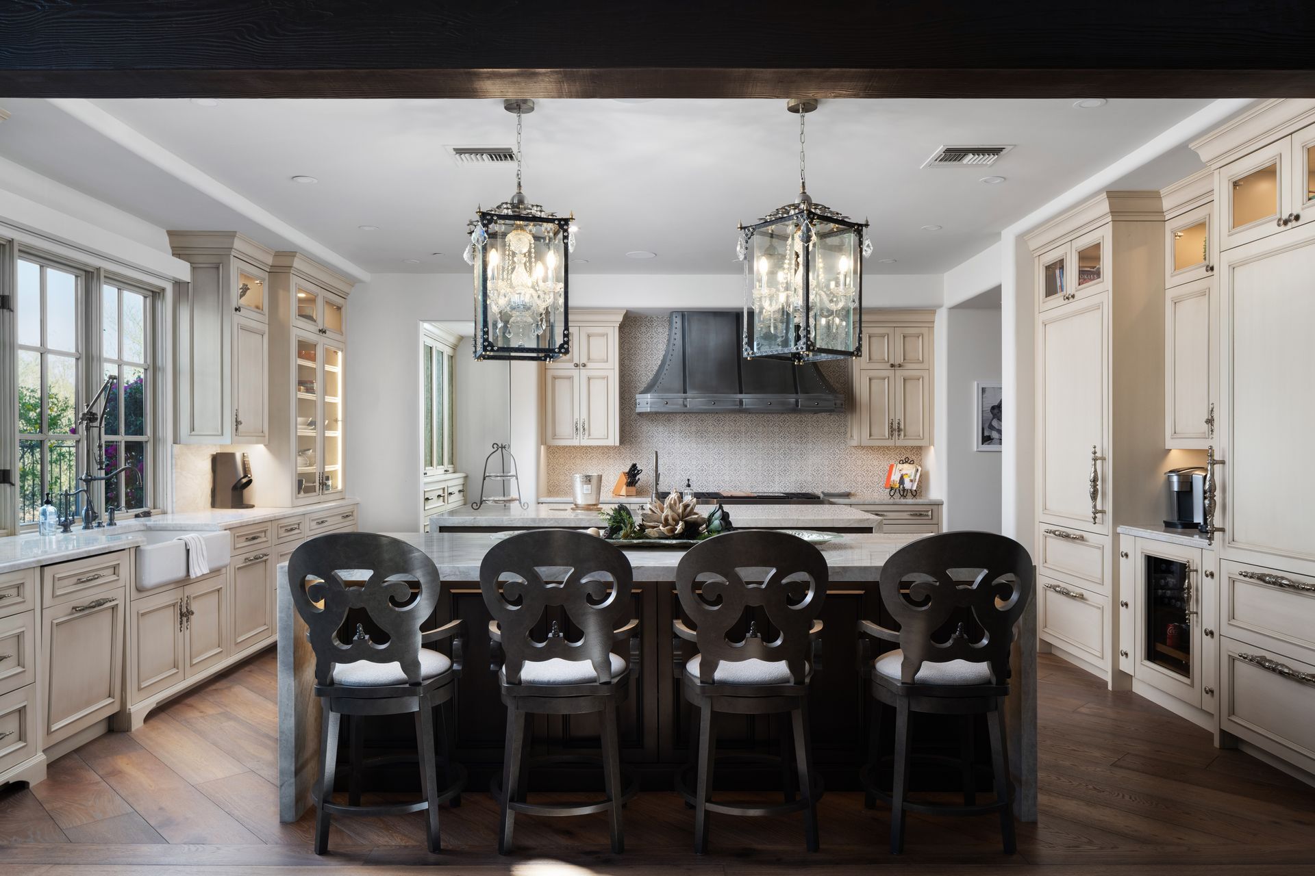 Luxurious kitchen with an island, cabinets, bar stools, and chandeliers.