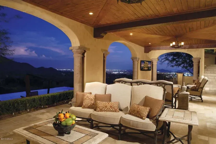 Outdoor patio with seating, stone columns, and city view at dusk.