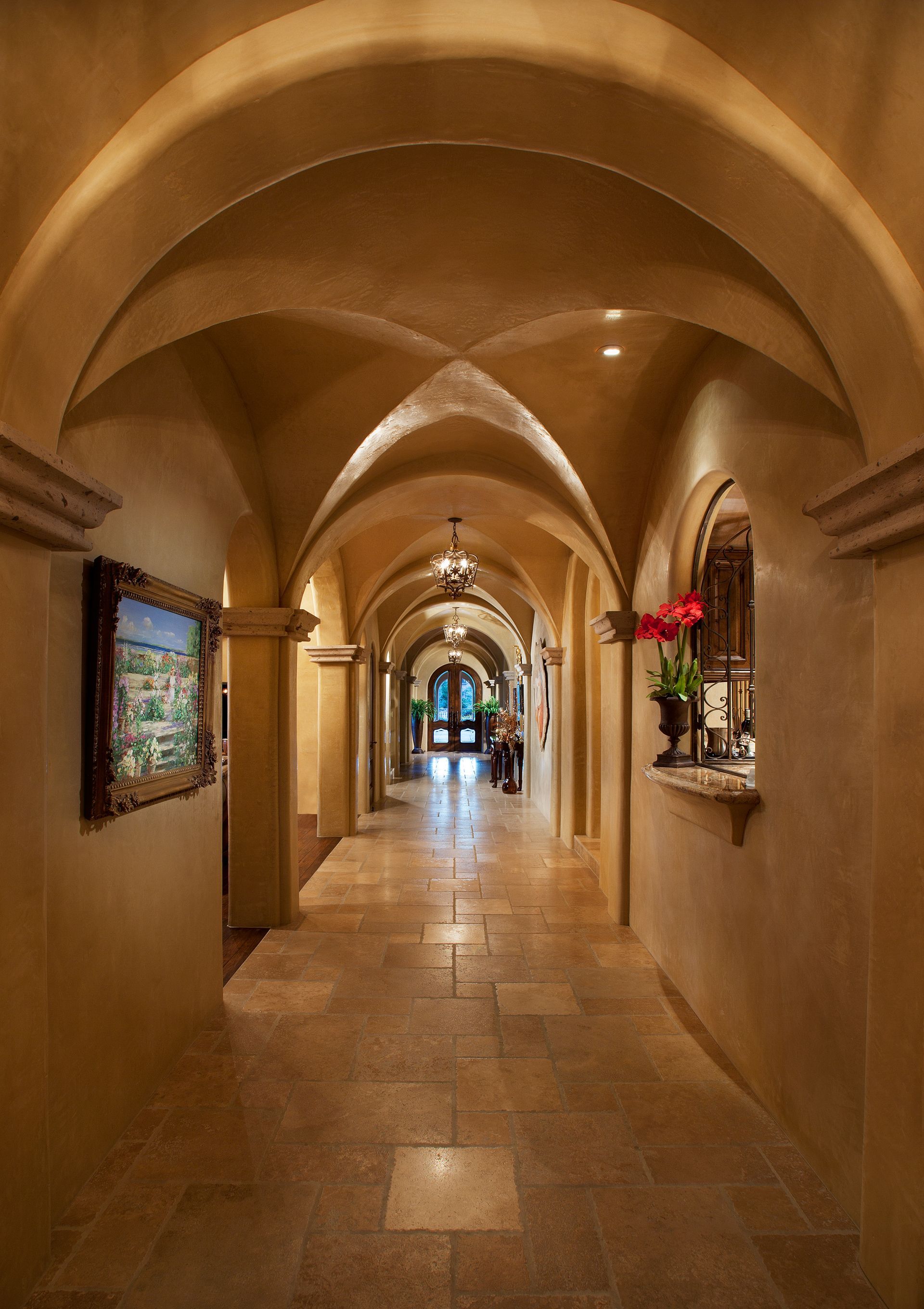 A long hallway with arches and a picture on the wall