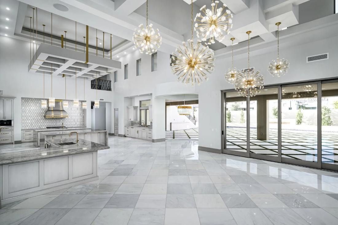 custom walk-in closet with white mirrored cabinets, an island, a chandelier, and marble floors