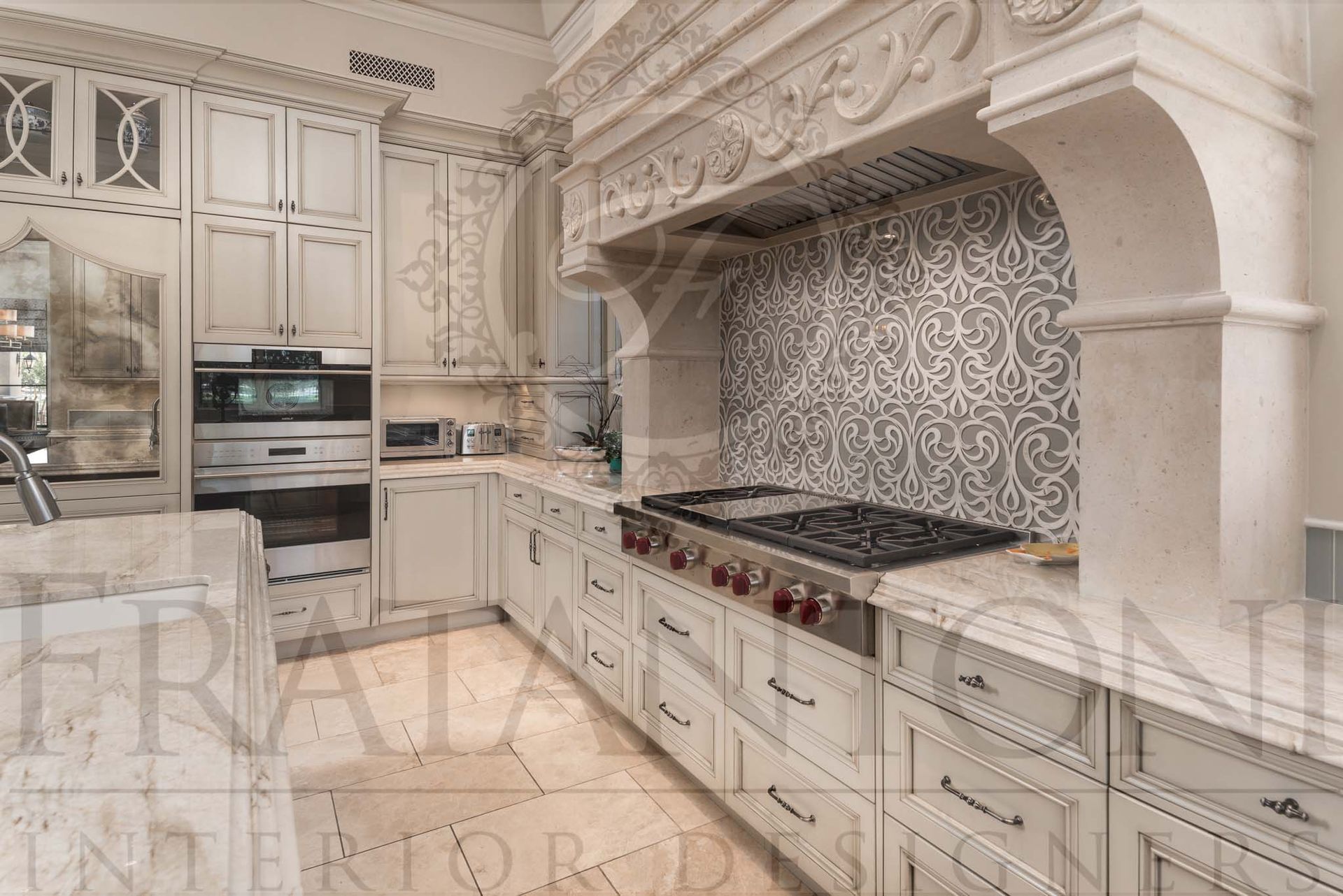 Elegant white kitchen with ornate cabinetry, built-in oven, patterned backsplash, and gas range under a carved stone hood designed by Fratantoni Interior Designers in scottsdale, Arizona
