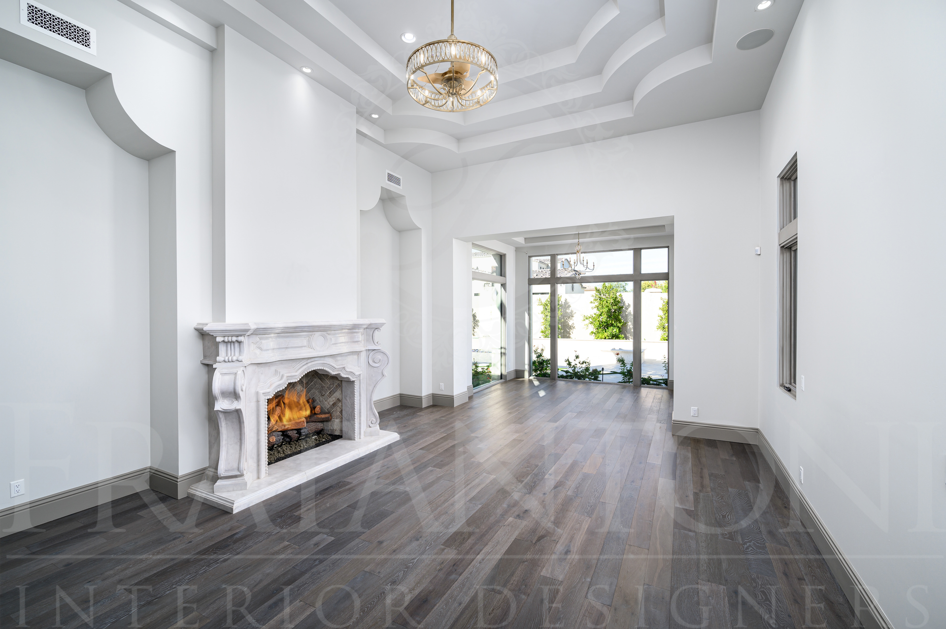 Bright luxury primary bedroom with white walls, dark hardwood floors, custom stone fireplace, and glass doors to courtyard in scottsdale, arizona