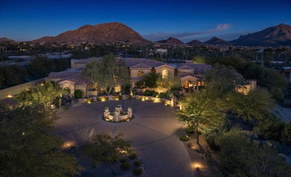 An aerial view of a large house at night with a mountain in the background.