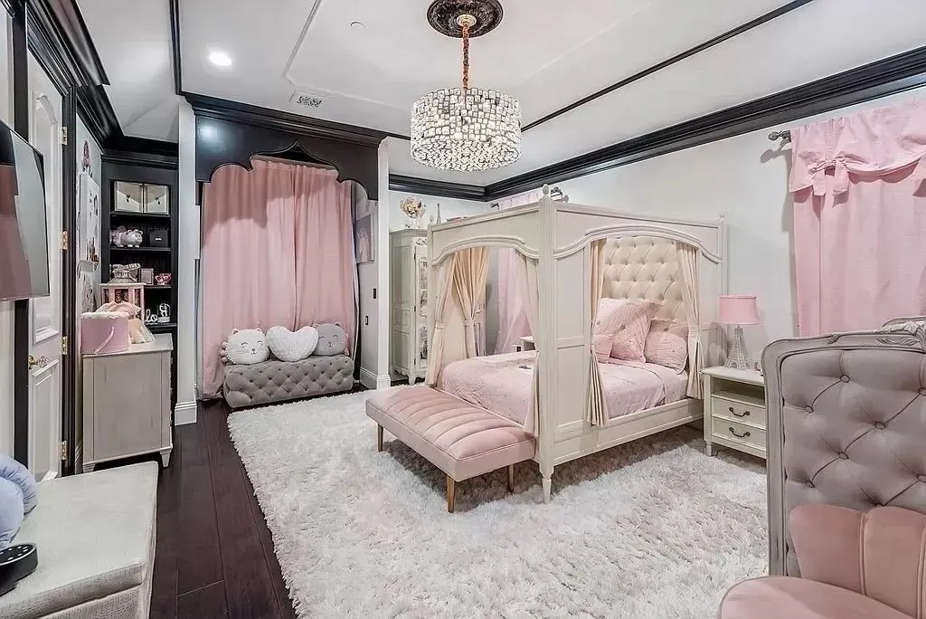 Pink and white bedroom with canopy bed, rug, and curtains.