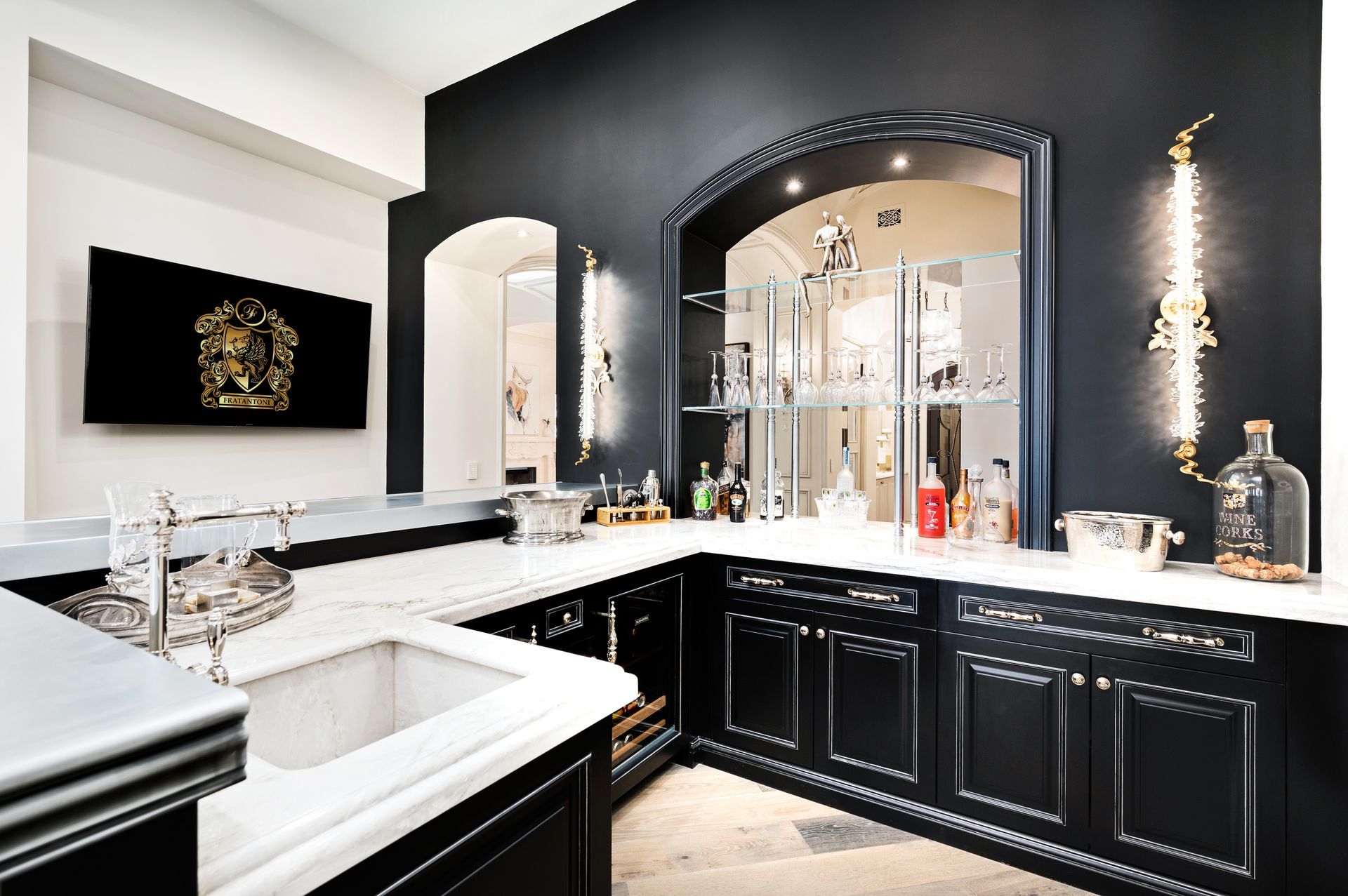 Elegant black home bar with white marble countertops, mirrored back, and gold accents.