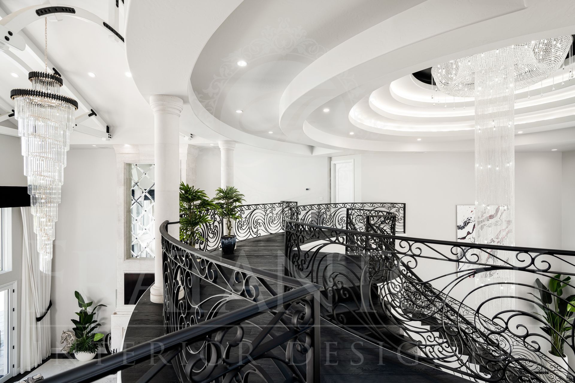 Elegant white and black interior balcony with curved staircase and ornate railing, crystal chandeliers.