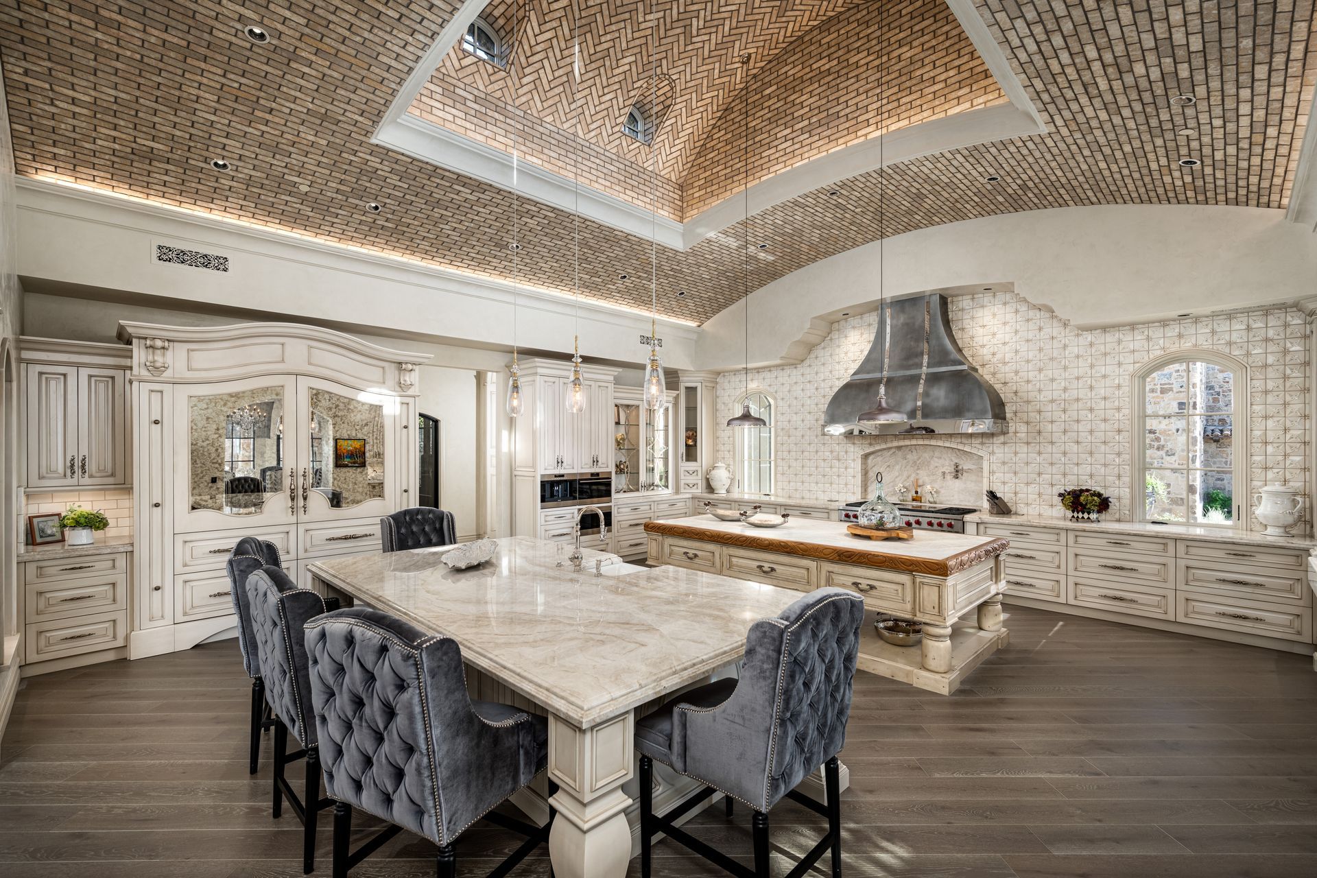 Luxurious kitchen with marble counters, gray velvet chairs, and a textured ceiling.