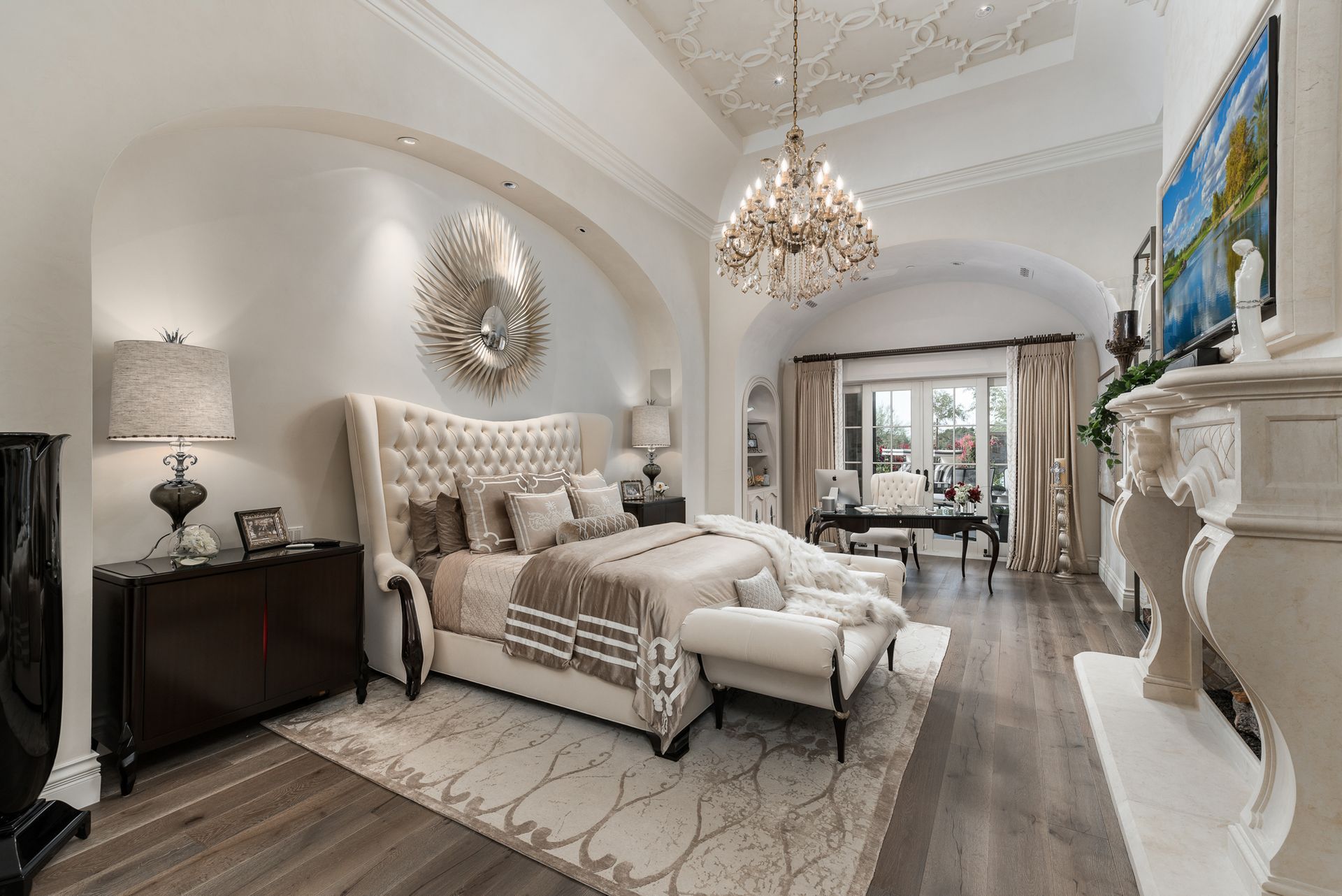 Elegant bedroom with high ceilings, chandelier, large bed, and fireplace.