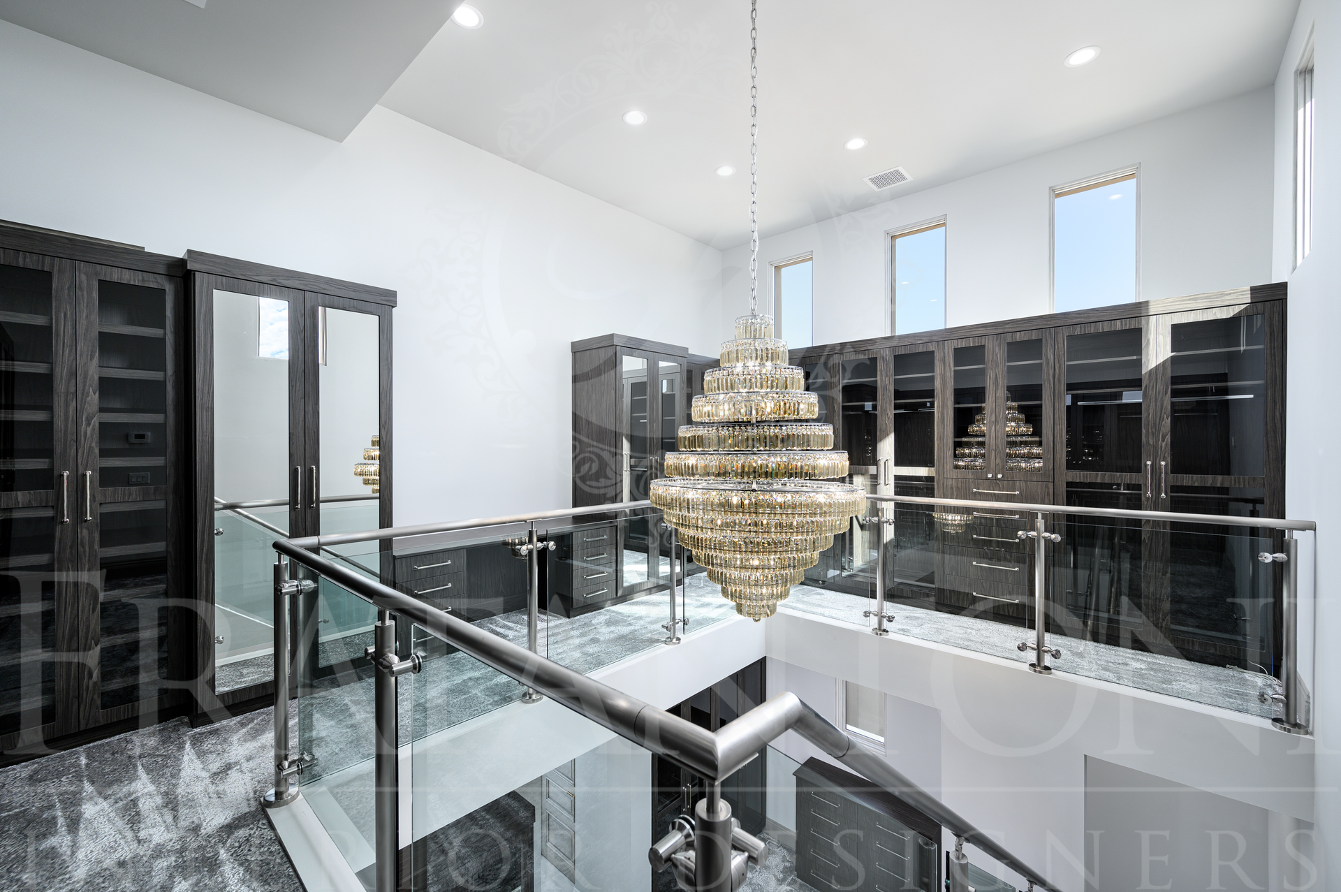 Modern staircase with glass railings and a large chandelier in a bright custom closet in scottsdale, Arizona.