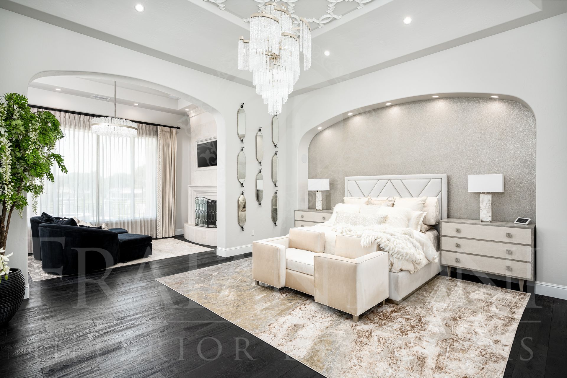 Elegant bedroom with a chandelier, detailed ceiling, king sized bed, seating area, fireplace, and dark wood floors designed by Fratantoni Interior Designers in Scottsdale, Arizona