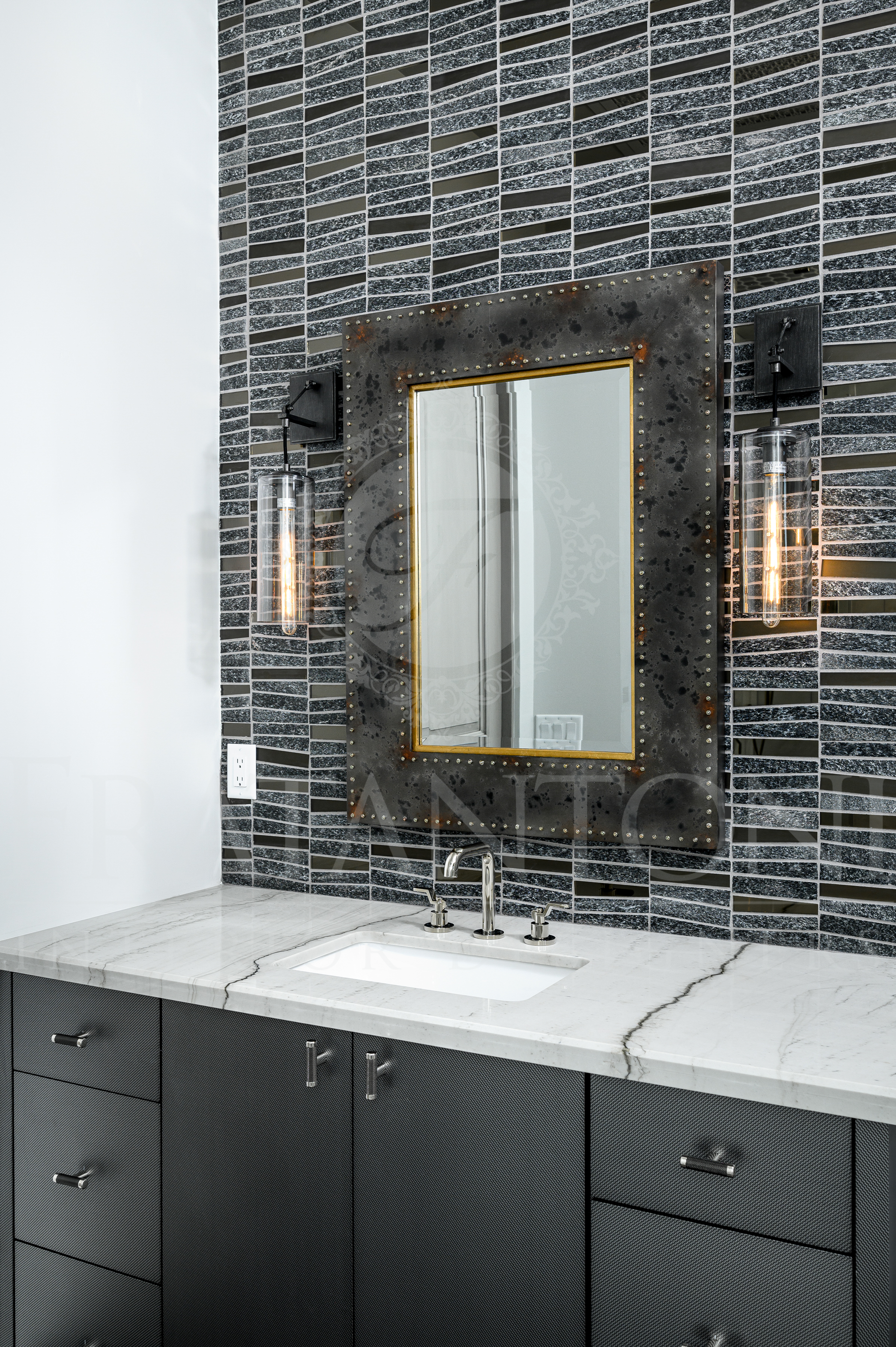 Modern bathroom with black tiled walls, white marble countertops, black custom vanity, and a framed mirror with sconces designed by Fratantoni Interior designers