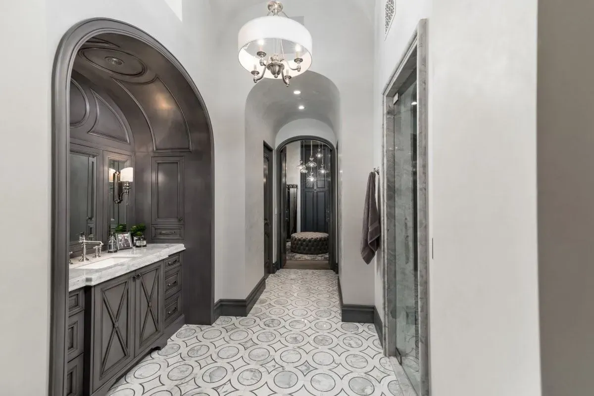 Hallway with dark gray vanity, patterned floor, and arched doorways.