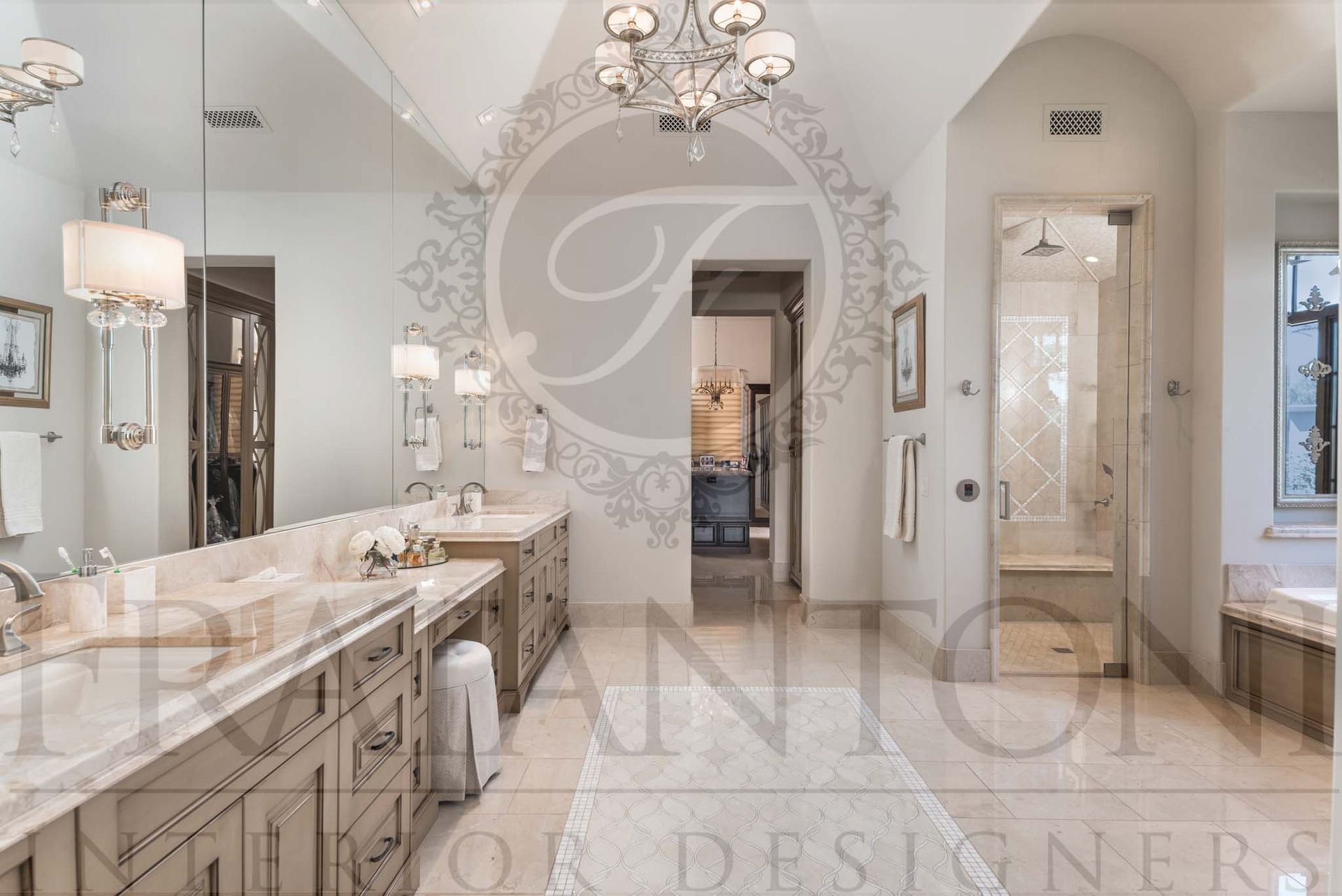 Elegant bathroom with double vanity, a seated makeup vanity, chandeliers, marble tile, and an arched walk-in shower entry designed by Fratantoni Interior Designers.
