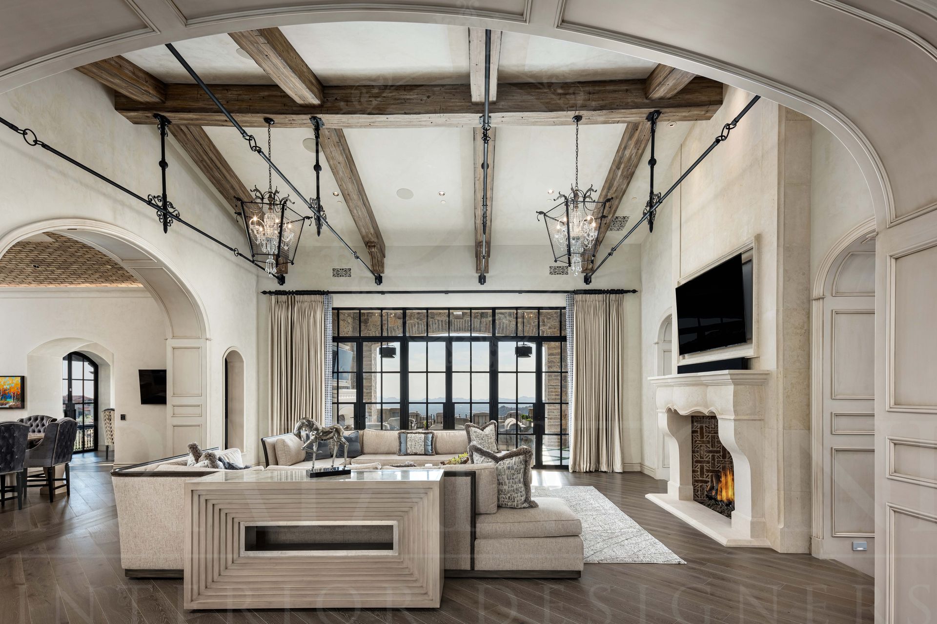 Elegant living room with high vaulted ceiling, exposed beams, fireplace, and large windows located in Silverleaf, DC Ranch Arizona