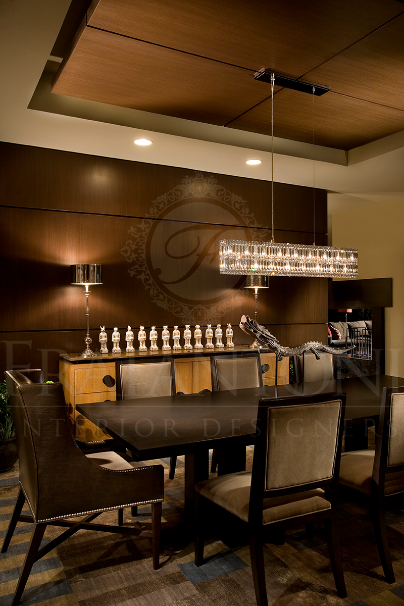 A modern dining room featuring a dark wooden table, upholstered chairs, a crystal chandelier, and a decorative sideboard.
