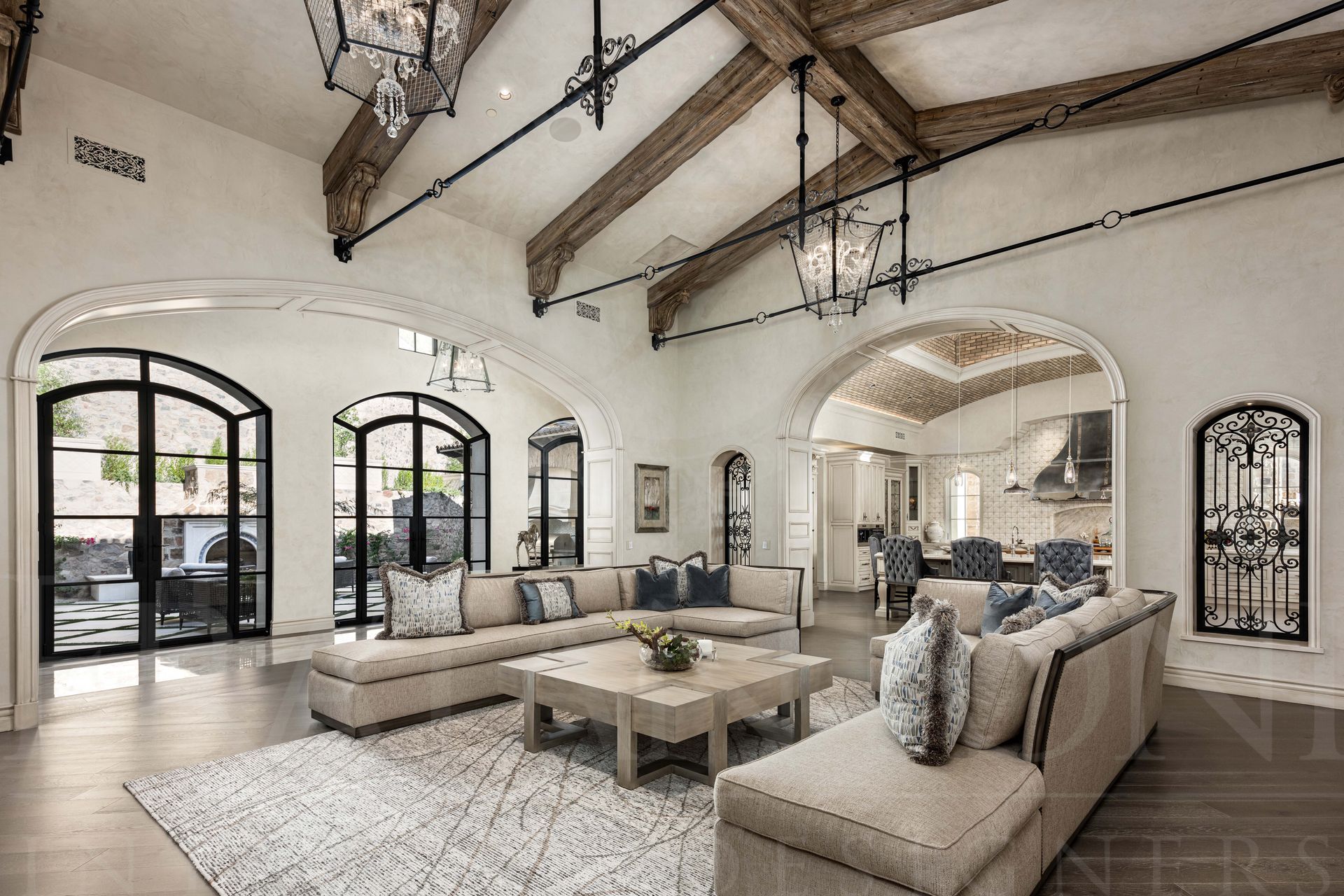 Elegant beige and white living room with arched windows, exposed wood beams, and two large sectional sofas designed by Fratantoni Interior Designers