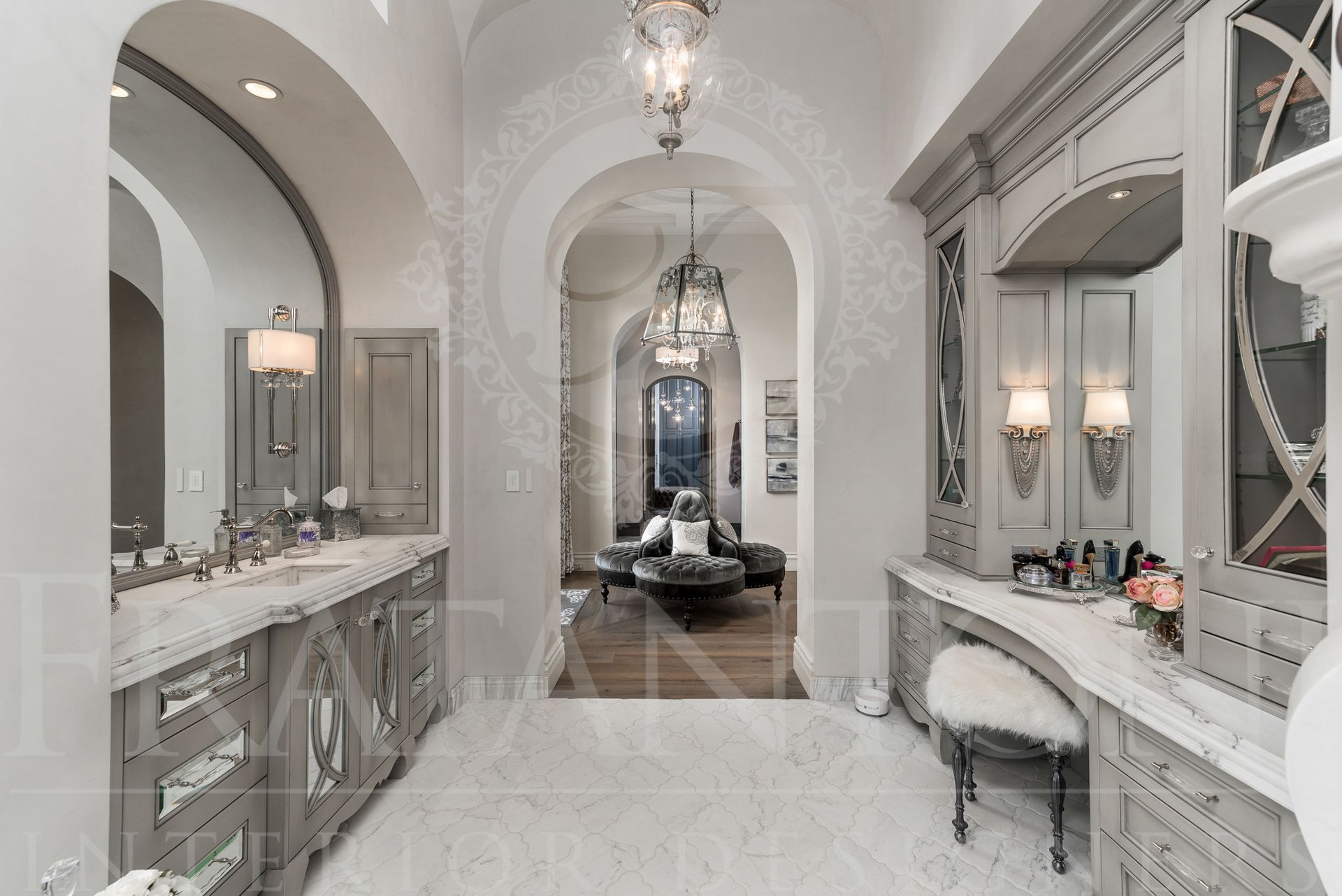Elegant grey bathroom with marble counters and ornate archway leading to a large walk-in closet. Large bathroom makeup vanity.