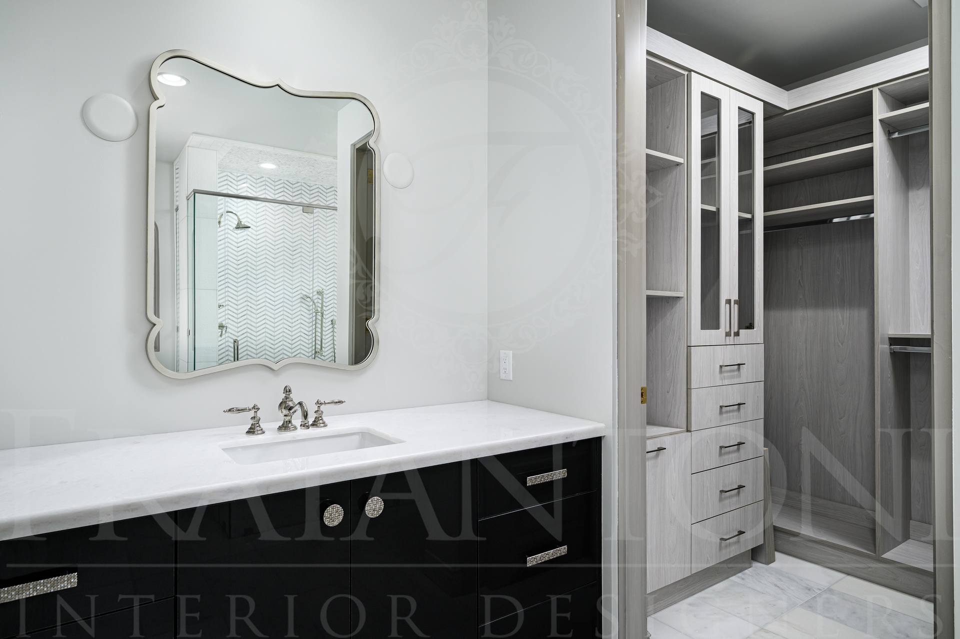 Luxury custom black bathroom vanity with white counters and a framed mirror beside an open walk-in closet in a modern interior designed by fratantoni interior designers