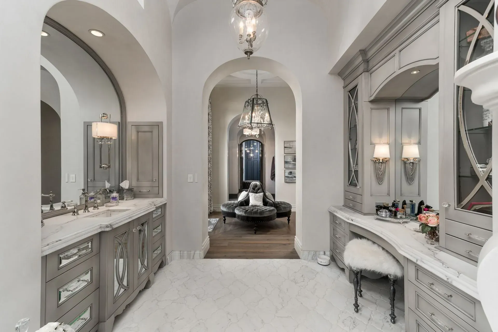Elegant bathroom with gray cabinets, marble countertops, ornate mirrors, and arched doorways.